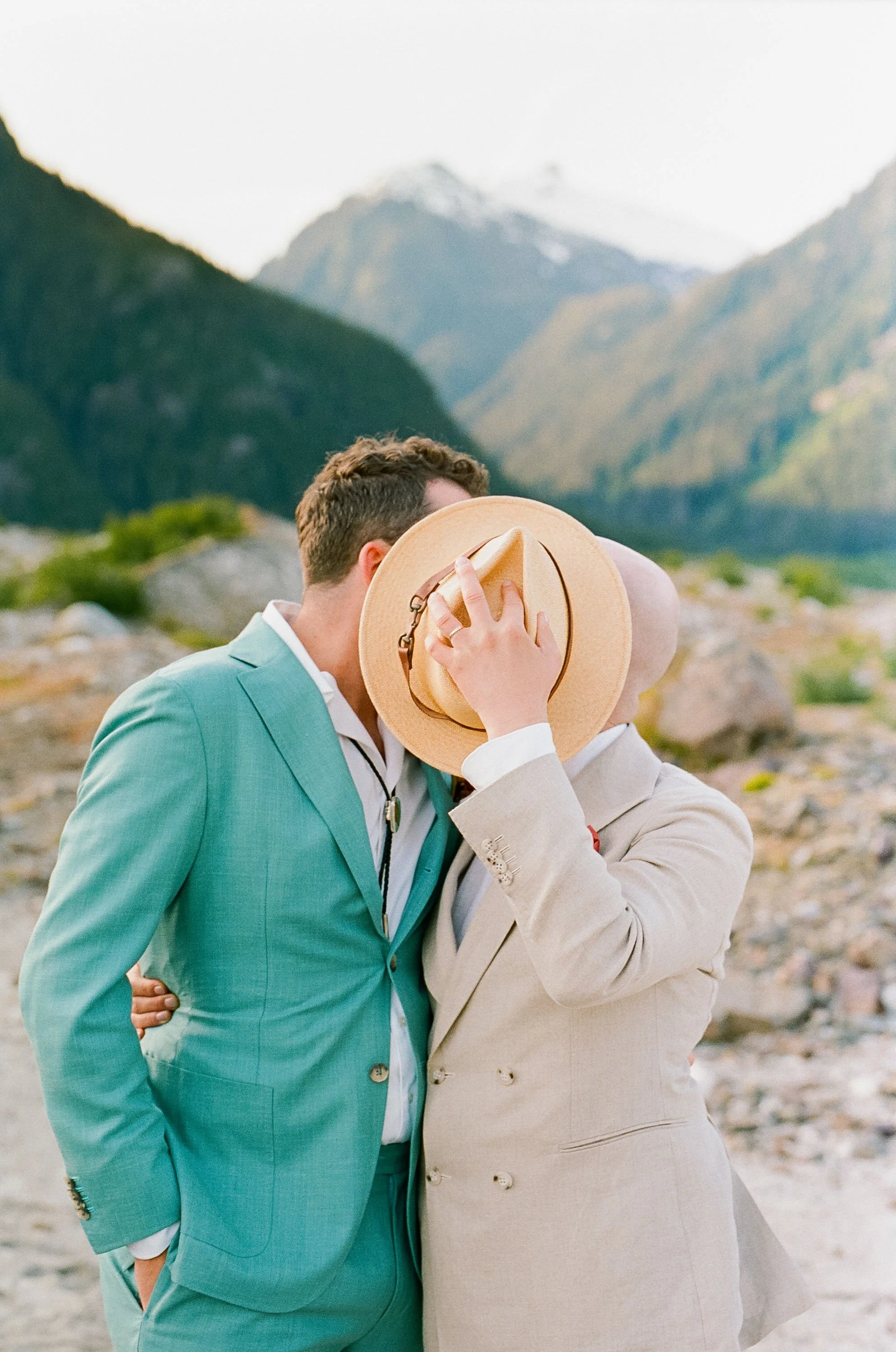 Portrait of two grooms in Alaska with turqouise suit and beige suit