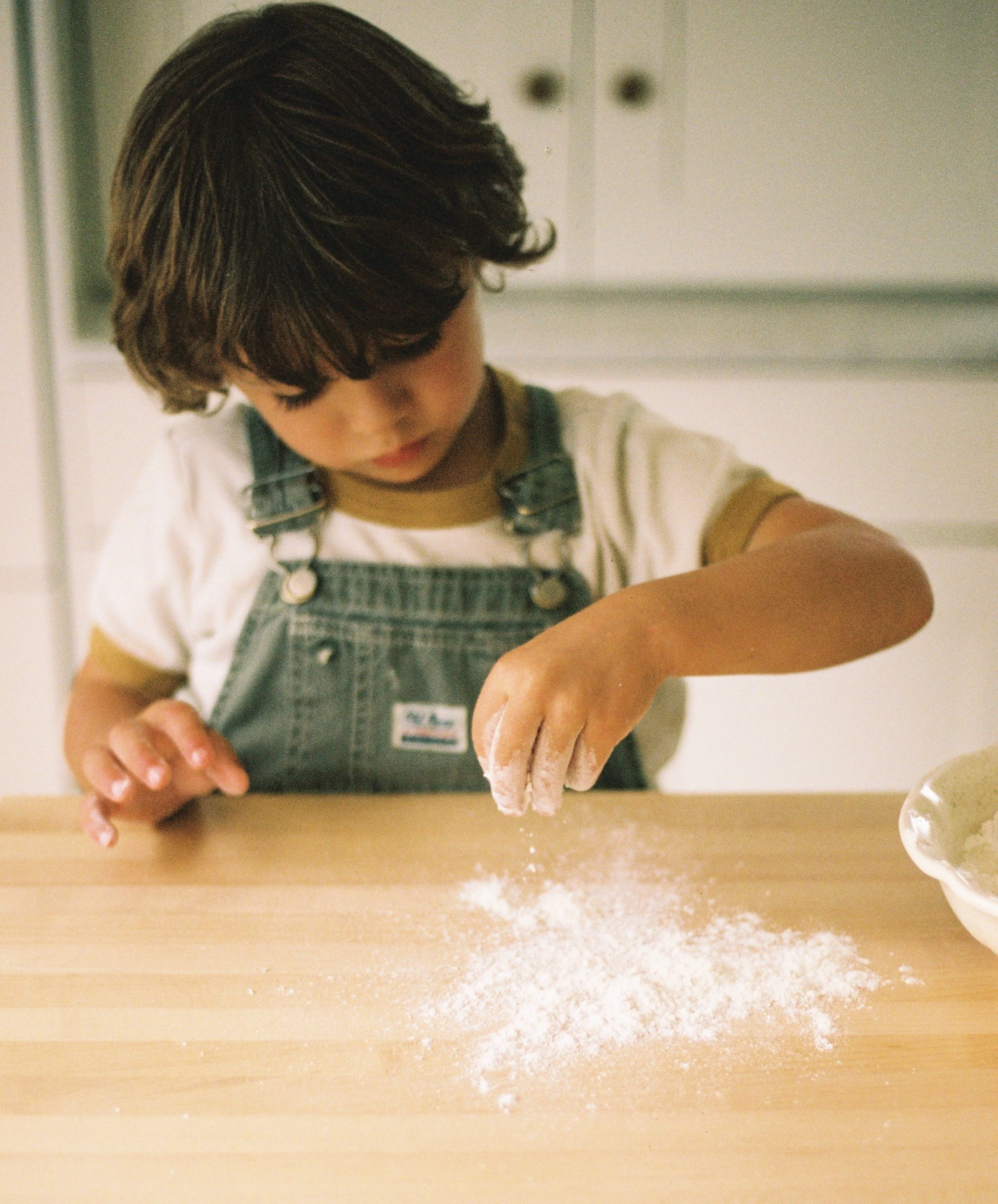 A child spreading flour on a counter.