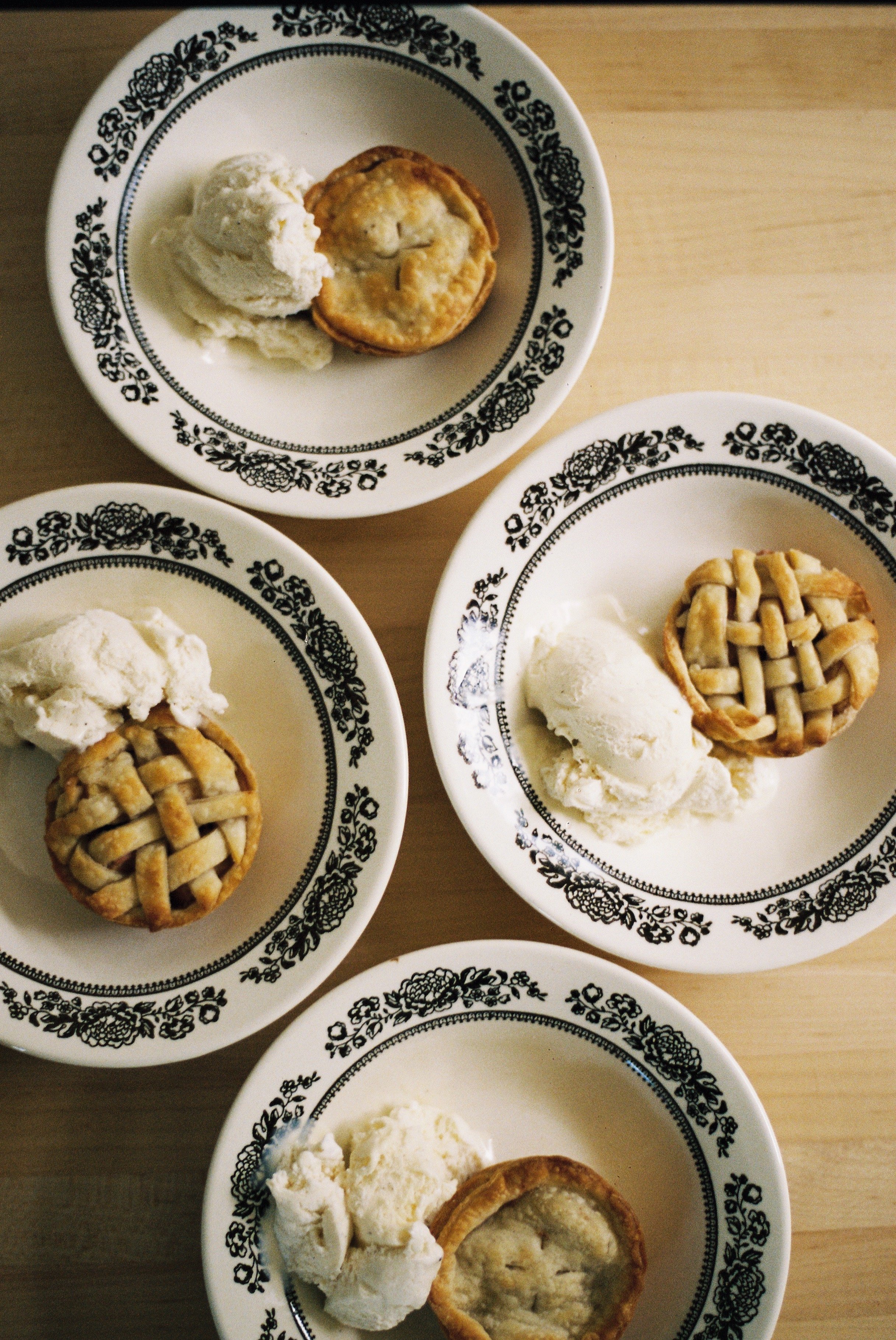 Small apple pies with vanilla ice cream in flowered ceramic bowls.