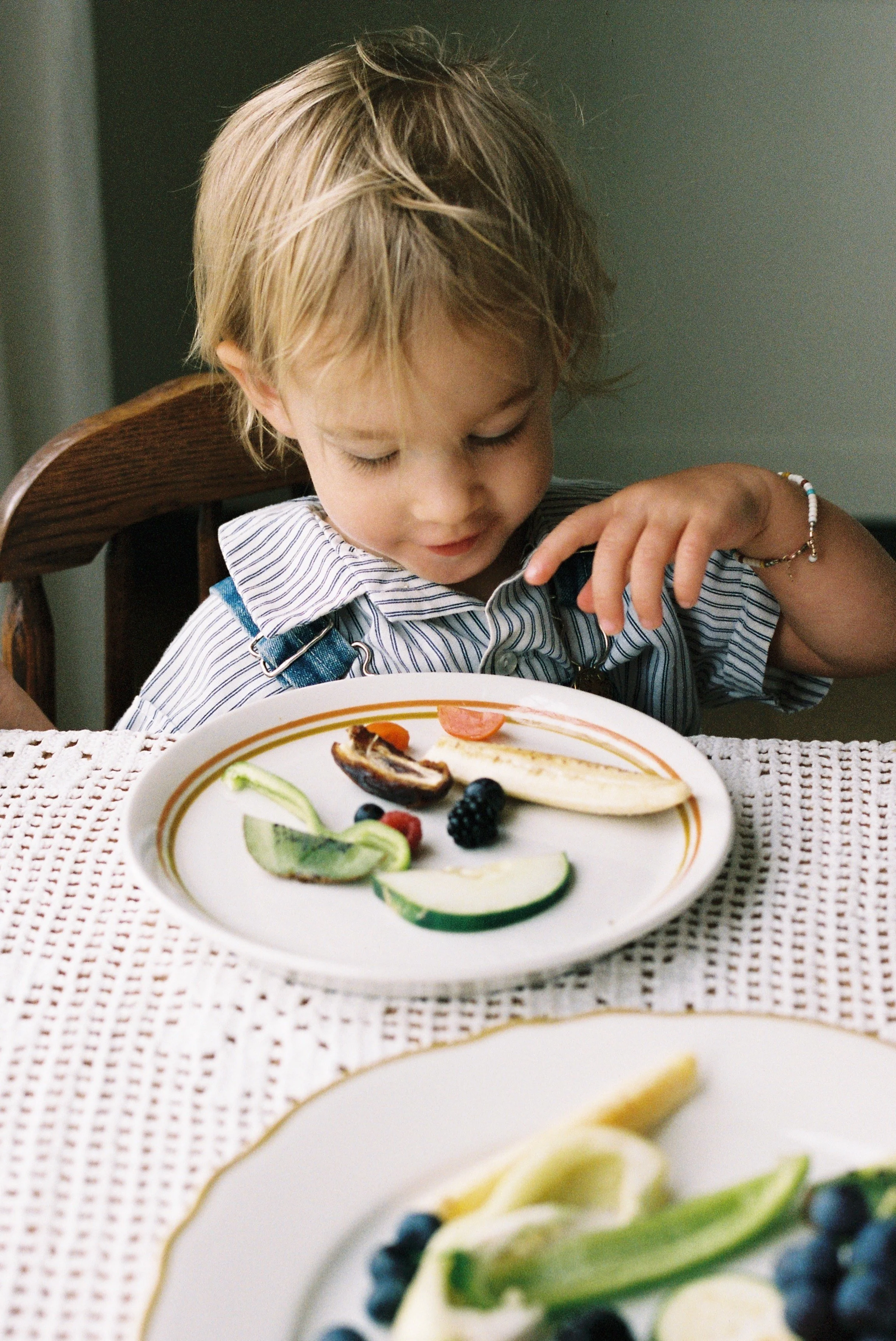 A small child smiles over a plate of food.