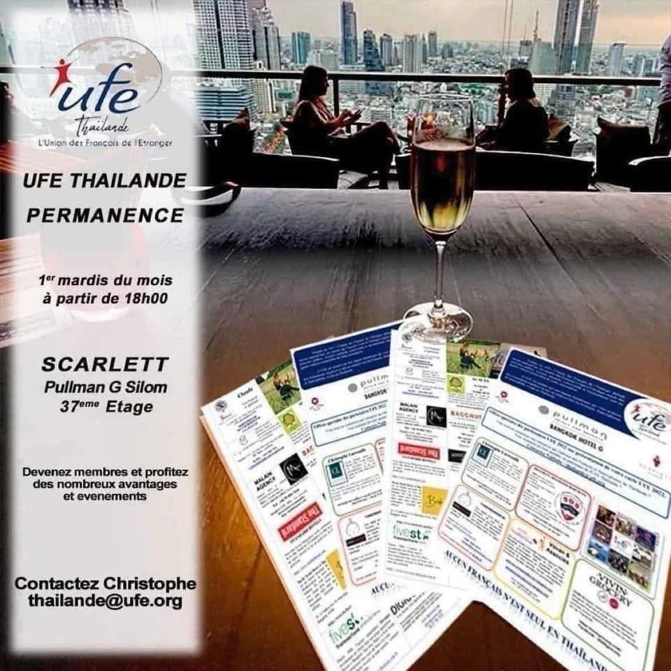 A promotional flyer for UFE Thailand hangs on a window. The flyer advertises monthly events on the first Tuesday at 6 PM, featuring a dinner at the Scarlett Pullman G Silom on the 37th floor. The flyer includes a contact email for Christophe and shows a city skyline with two people sitting and talking, seen from inside a modern building with large windows. In the foreground on a wooden table, there is a glass of dark beverage and some flyers.