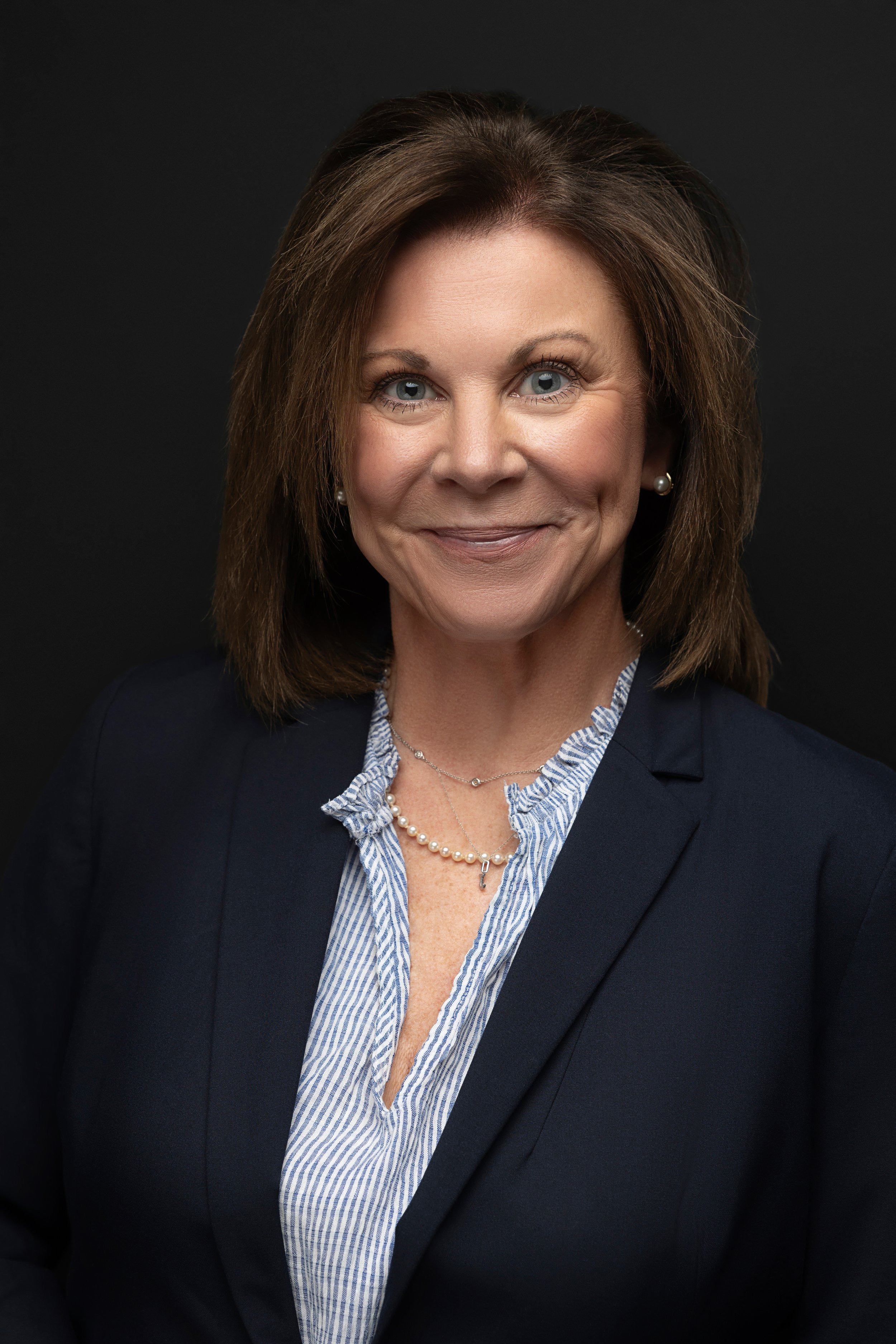 Professional headshot of a confident woman in a navy blazer, photographed in a Memphis Tennessee studio by Hadonica’s Photography