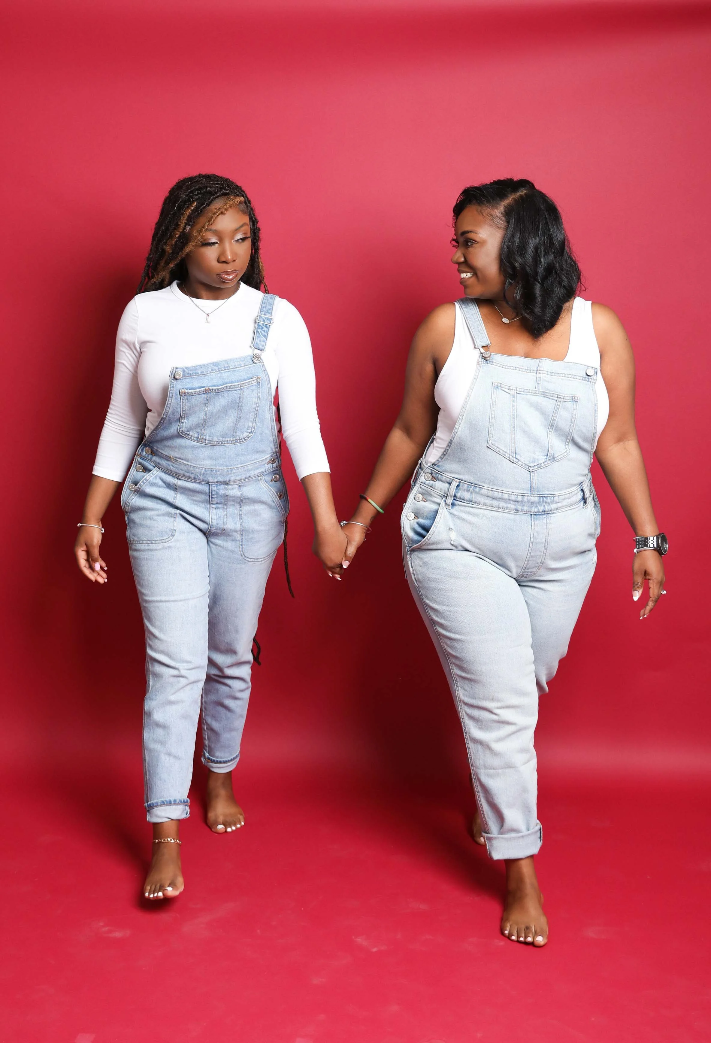 Mother and senior daughter holding hands and walking together in matching denim outfits during a studio photoshoot in Memphis TN