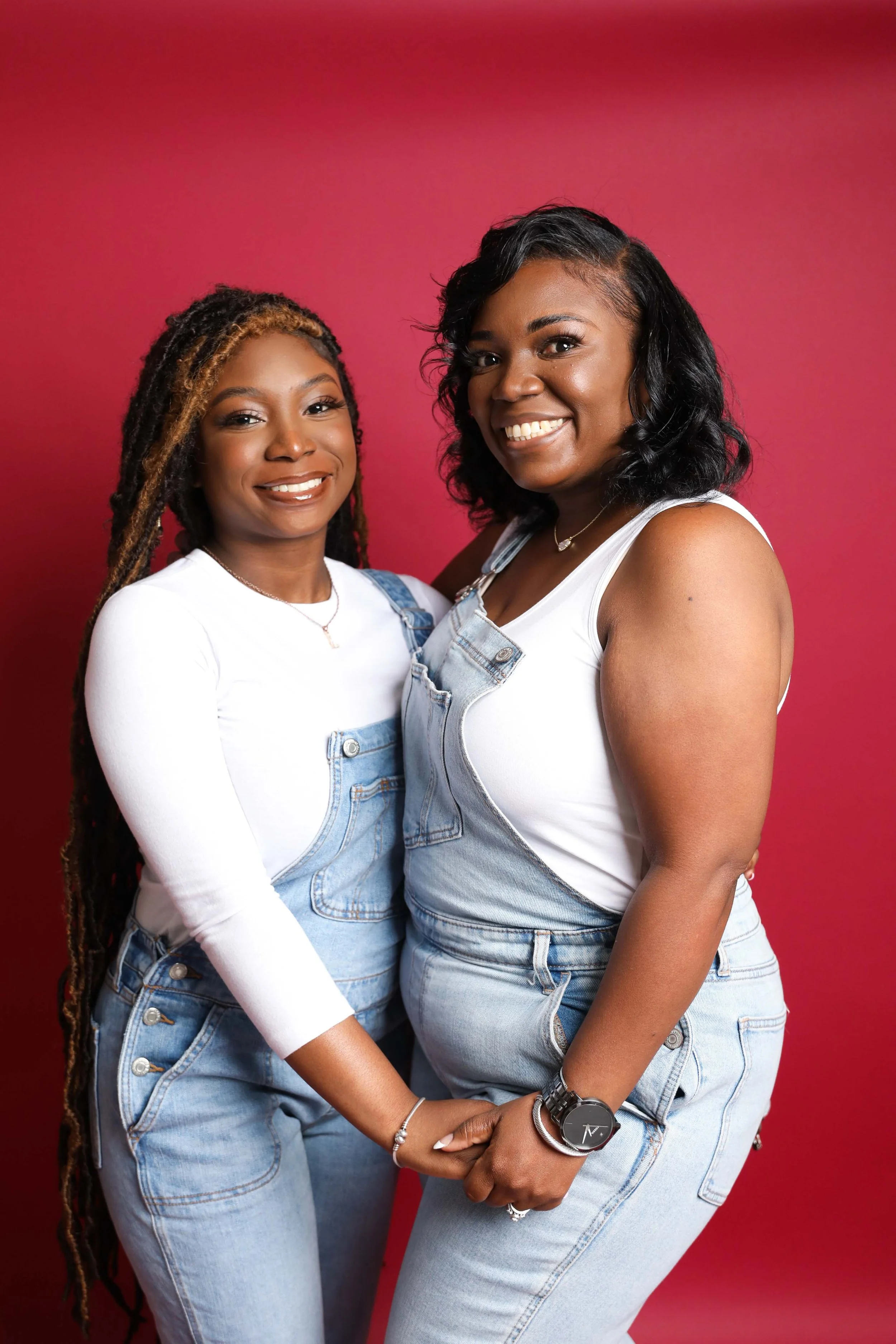 Mother and senior daughter standing together holding hands and smiling at camera in Memphis portrait studio
