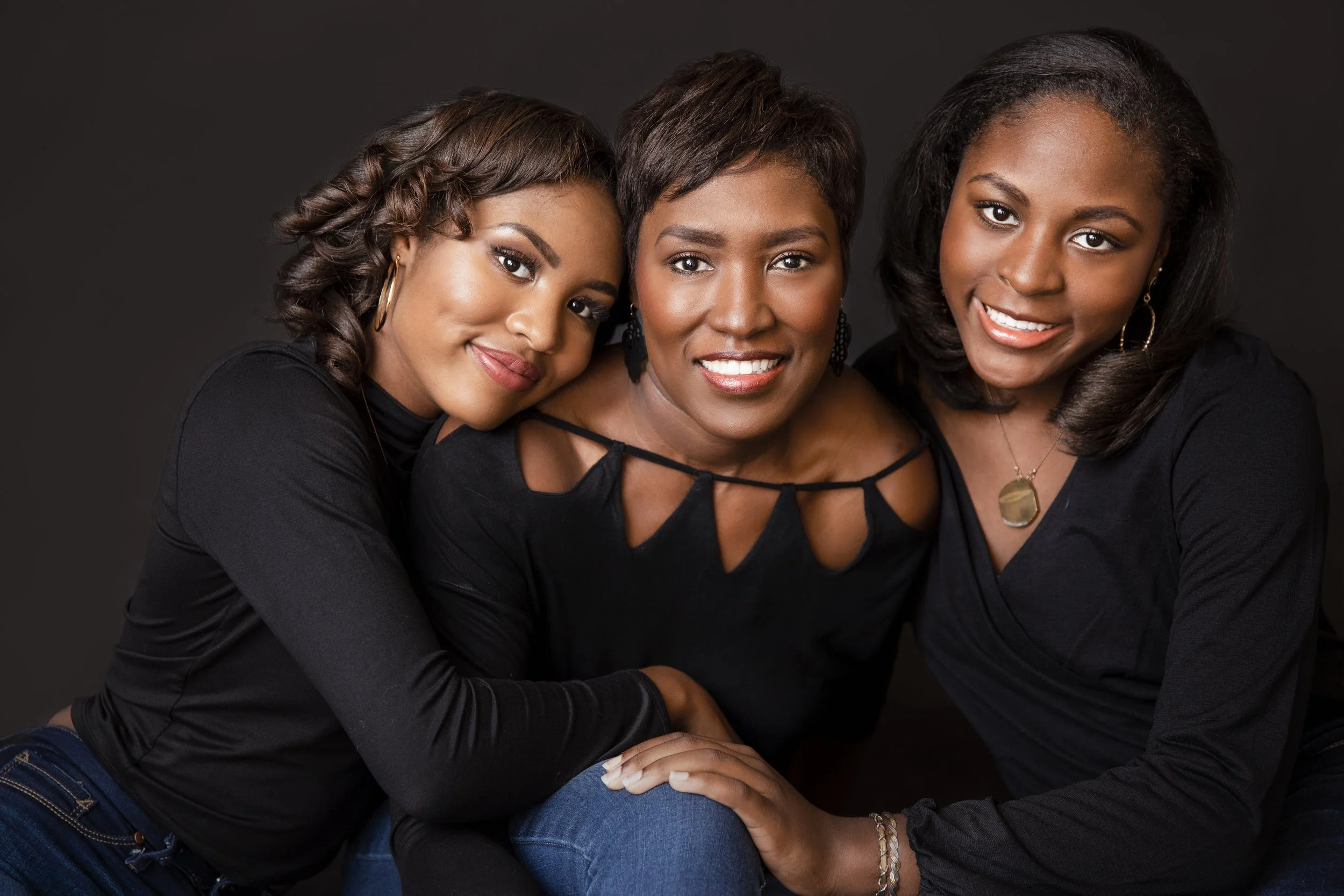 Three women posing together in black outfits during a professional studio portrait session in Memphis TN