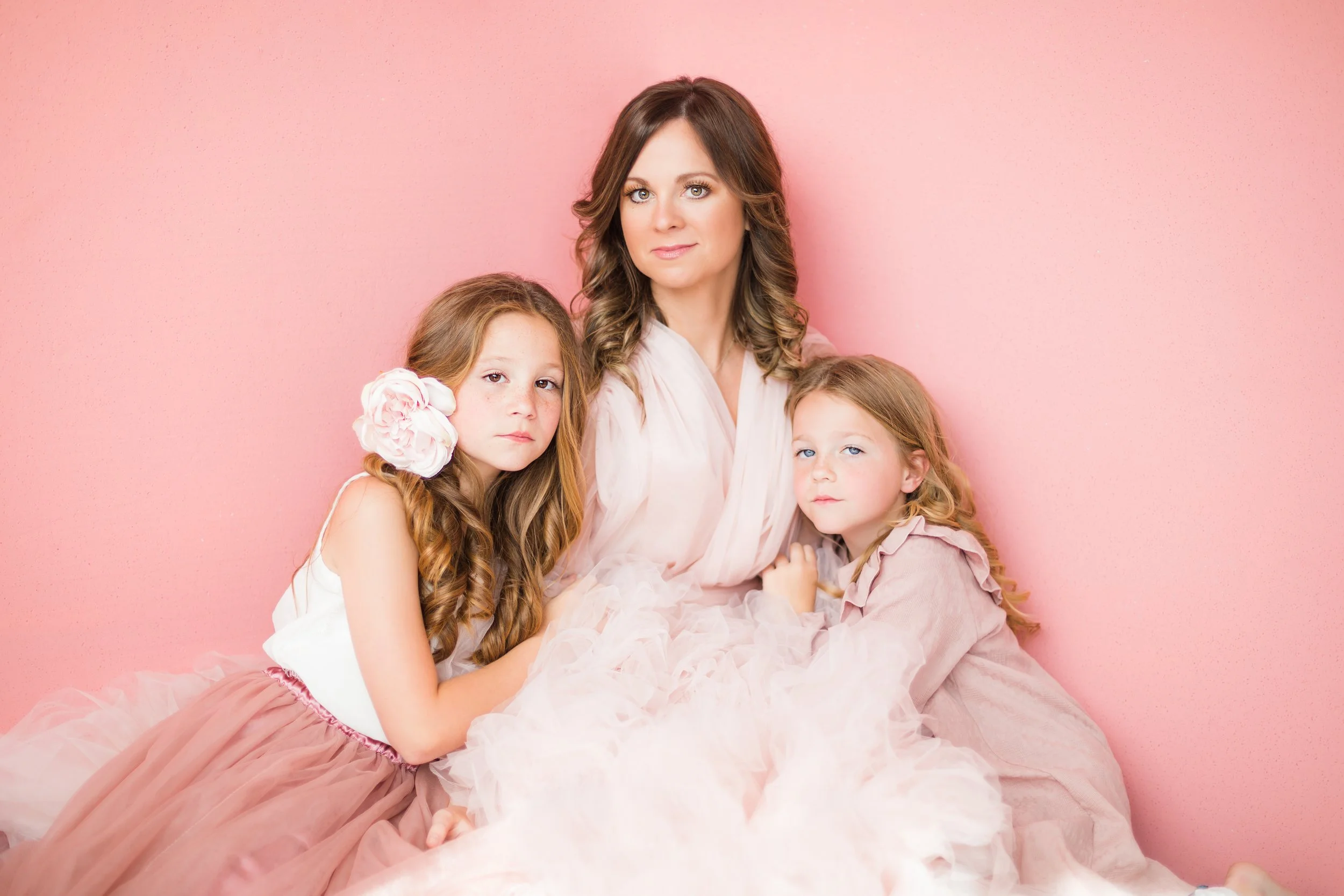Mother with two young daughters in soft pink dresses during a luxury studio family portrait session in Memphis TN