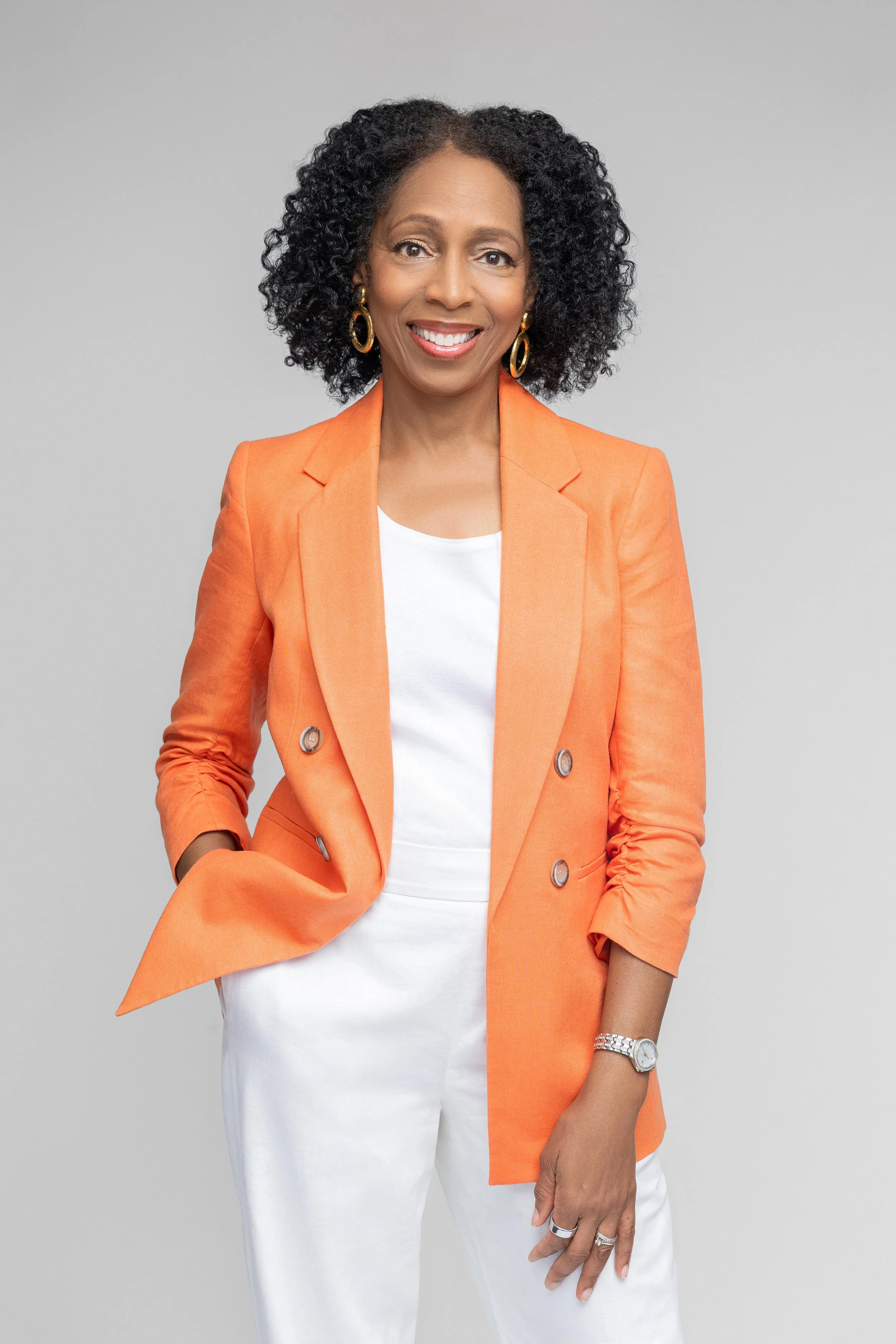 Confident therapist professional portrait in orange blazer standing against a white background in Memphis photography studio