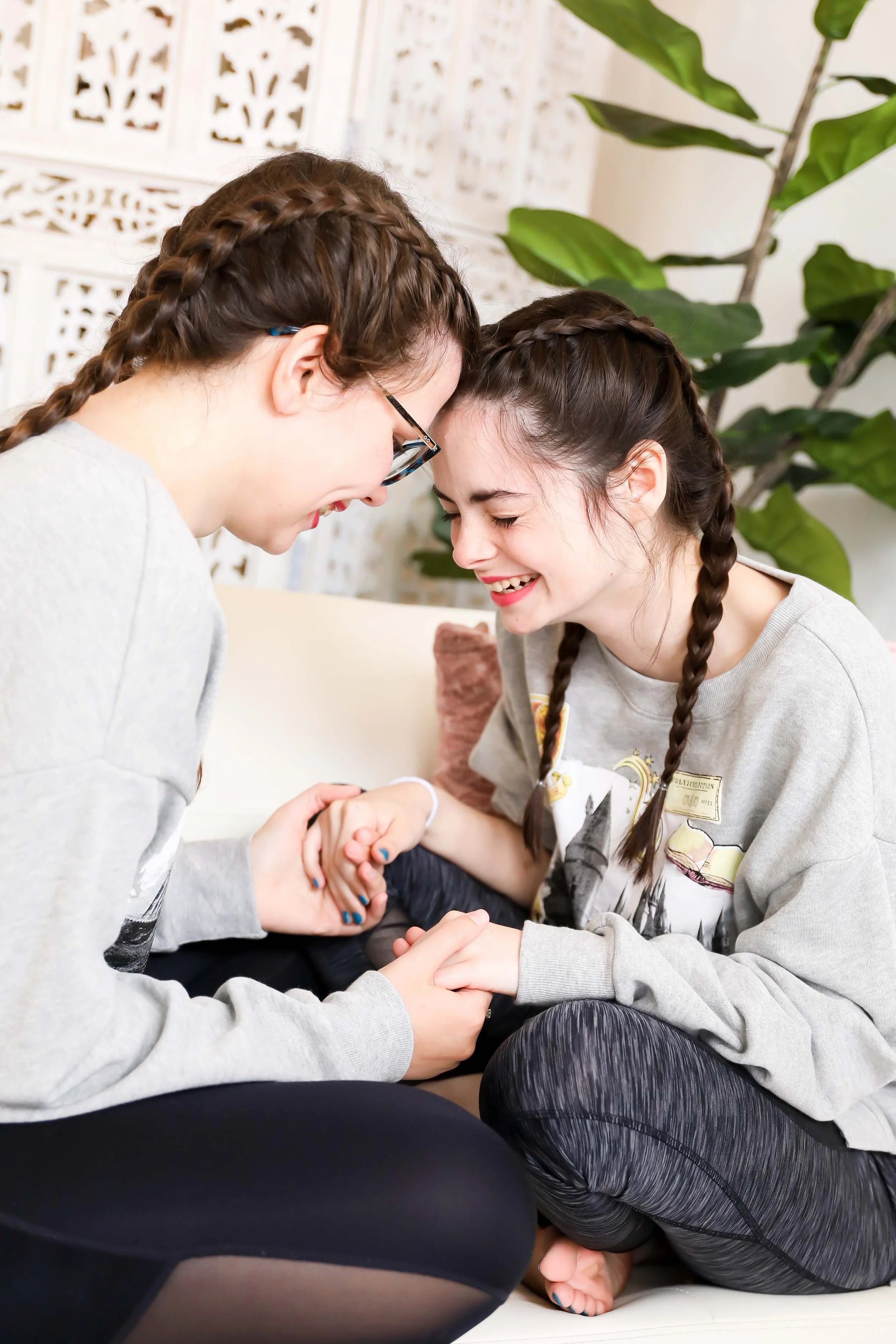 Mother and daughter holding hands and laughing during indoor senior portrait session in Memphis Tennessee