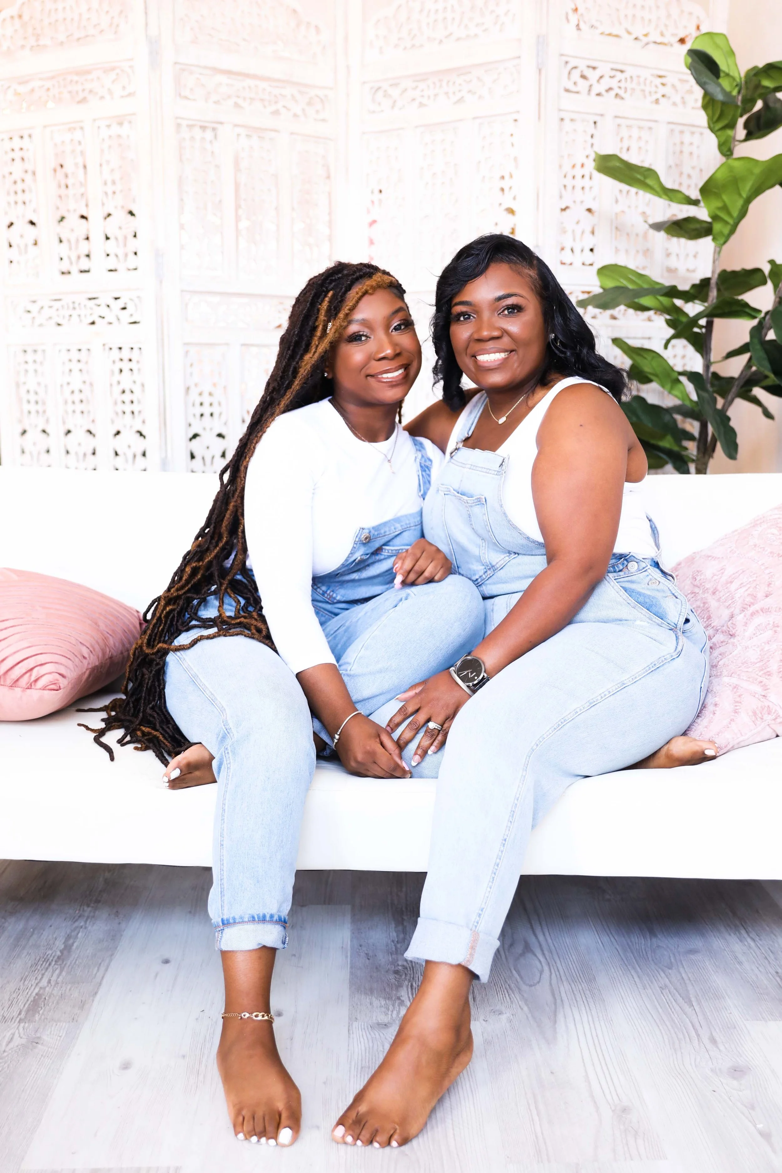 Mother and senior daughter sitting on couch smiling during lifestyle photoshoot in Memphis studio
