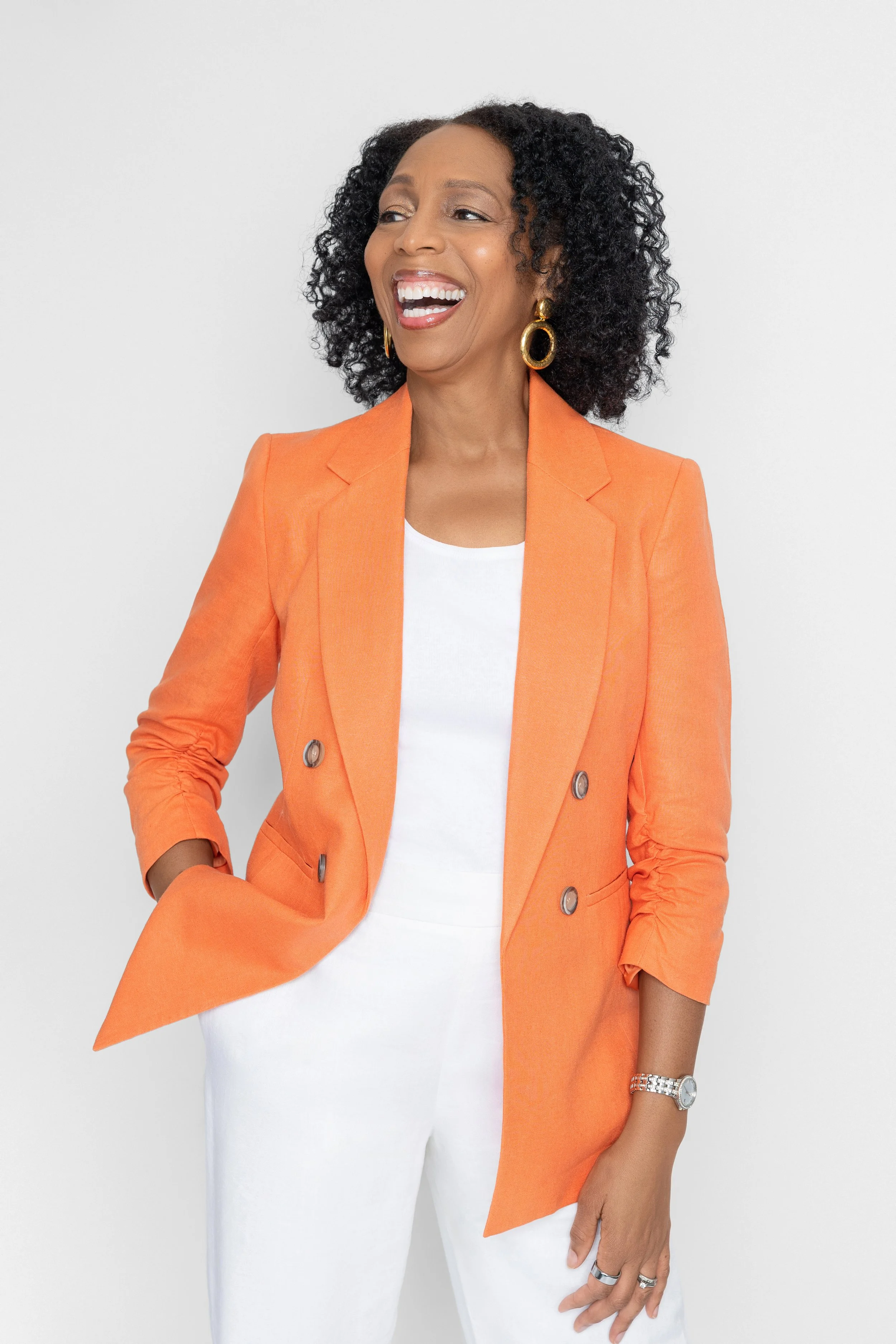 Candid personal branding photo of a therapist laughing in an orange blazer against a neutral background in Memphis studio