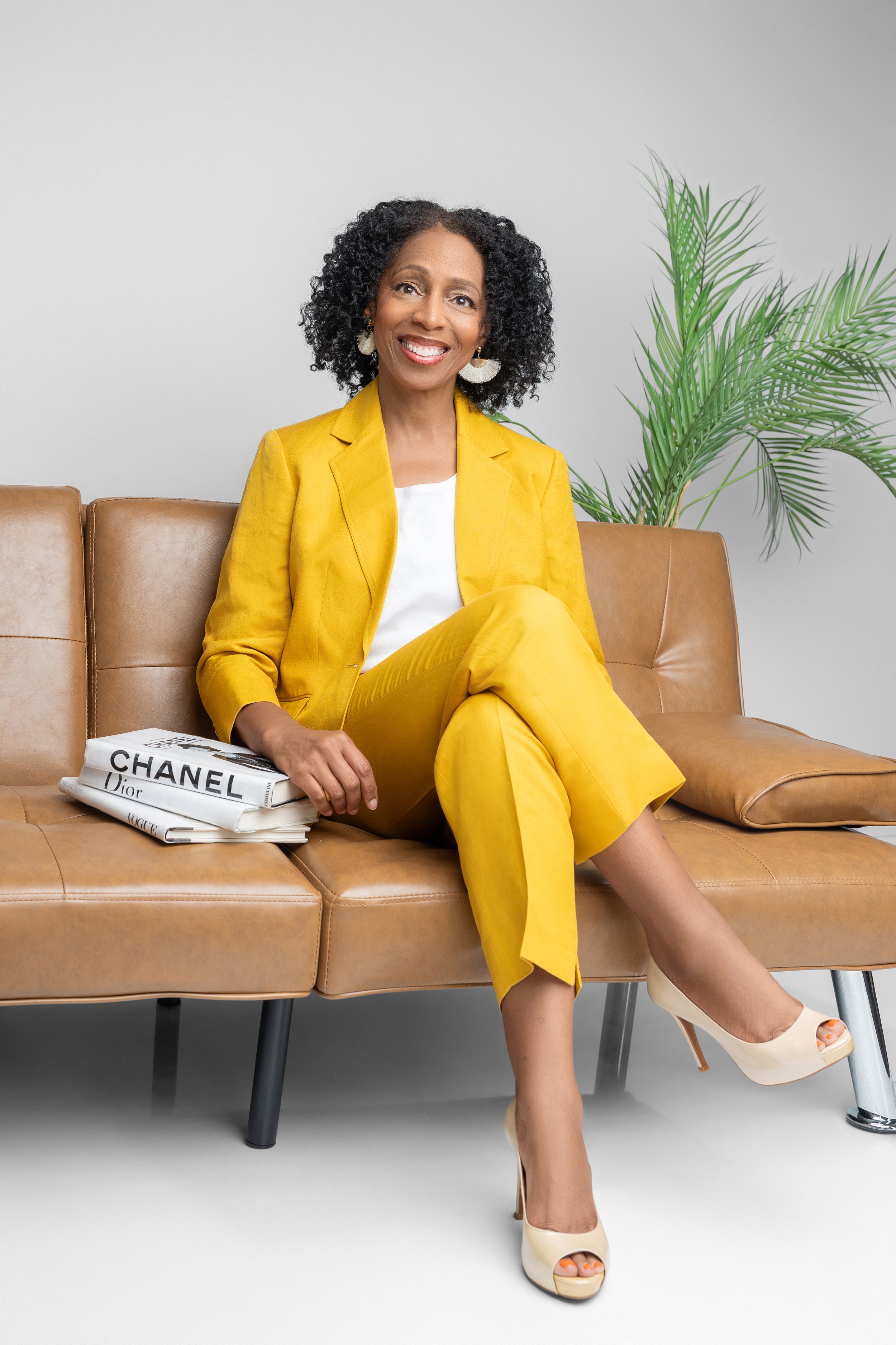 Full body therapist branding photo of woman in yellow suit sitting on couch in Memphis photography studio