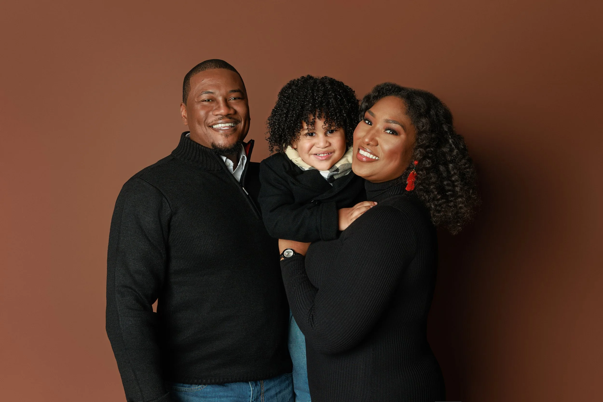 Family portrait of mother, father, and young son smiling in studio at Hadonica’s Photography in Memphis Tennessee