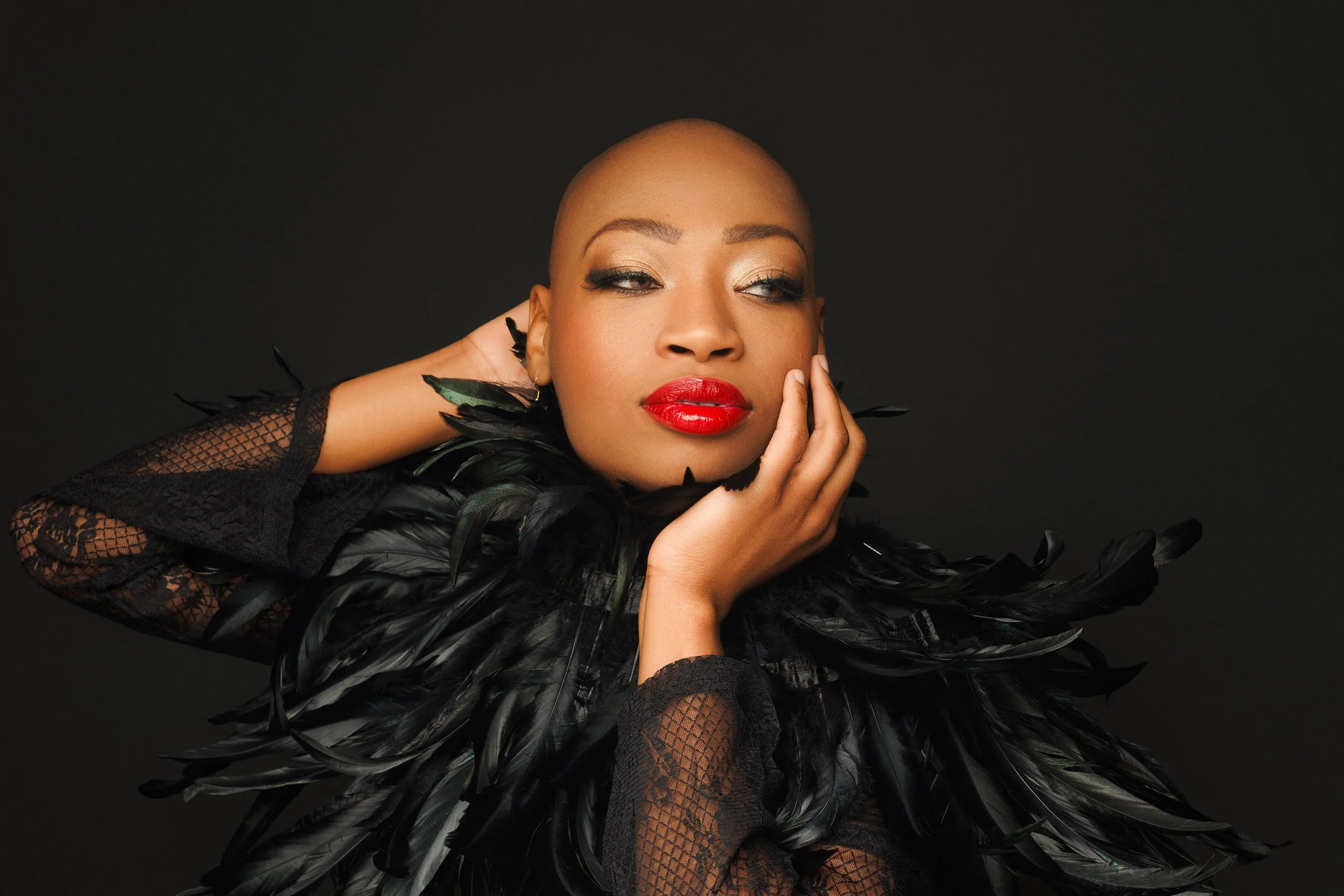 High end beauty boudoir portrait of woman with red lipstick and black feather collar, photographed in luxury Memphis studio by Hadonica’s Photography.
