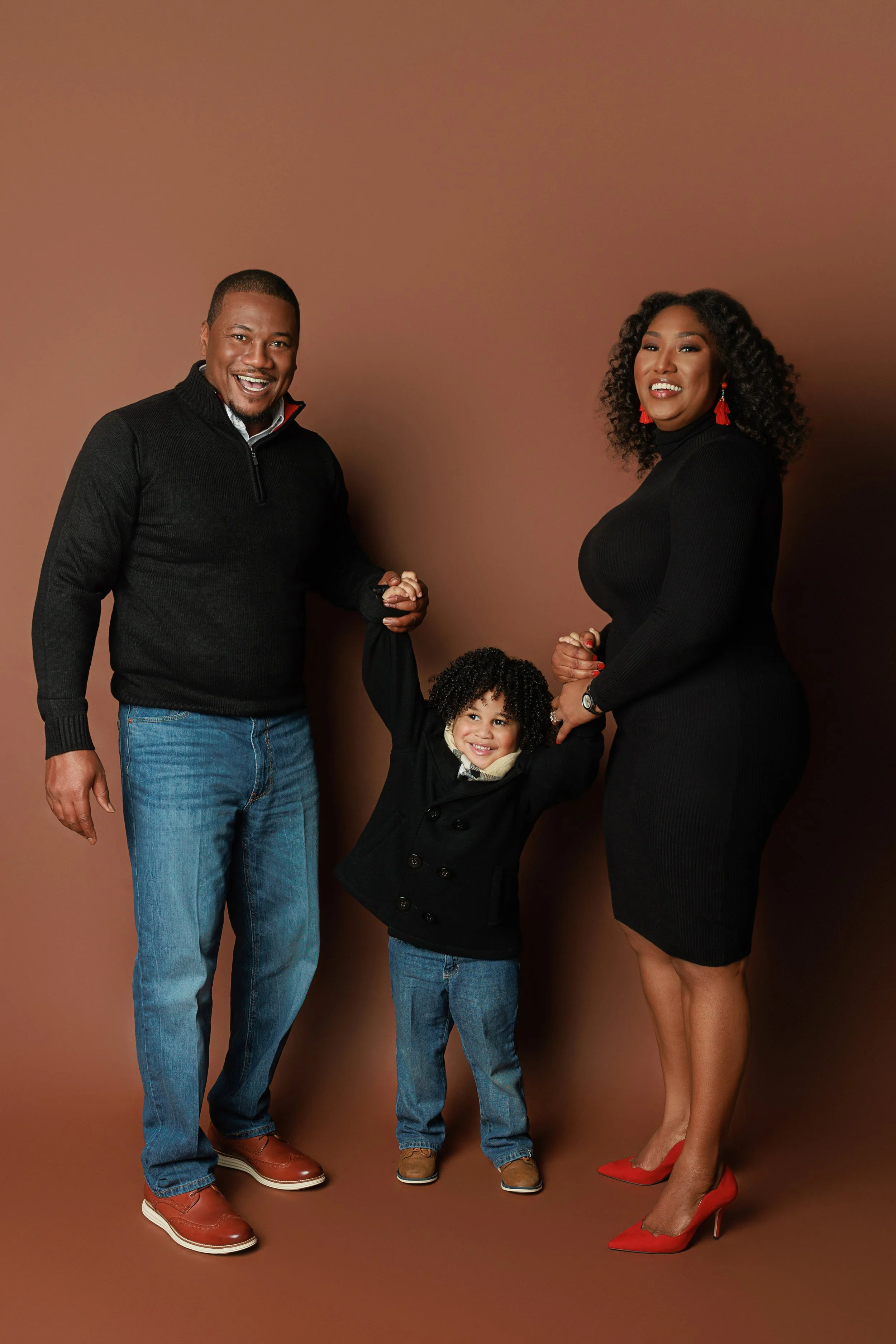 Full length family portrait of Mother, father, and young son holding hands in studio at Hadonica’s Photography in Memphis Tennessee