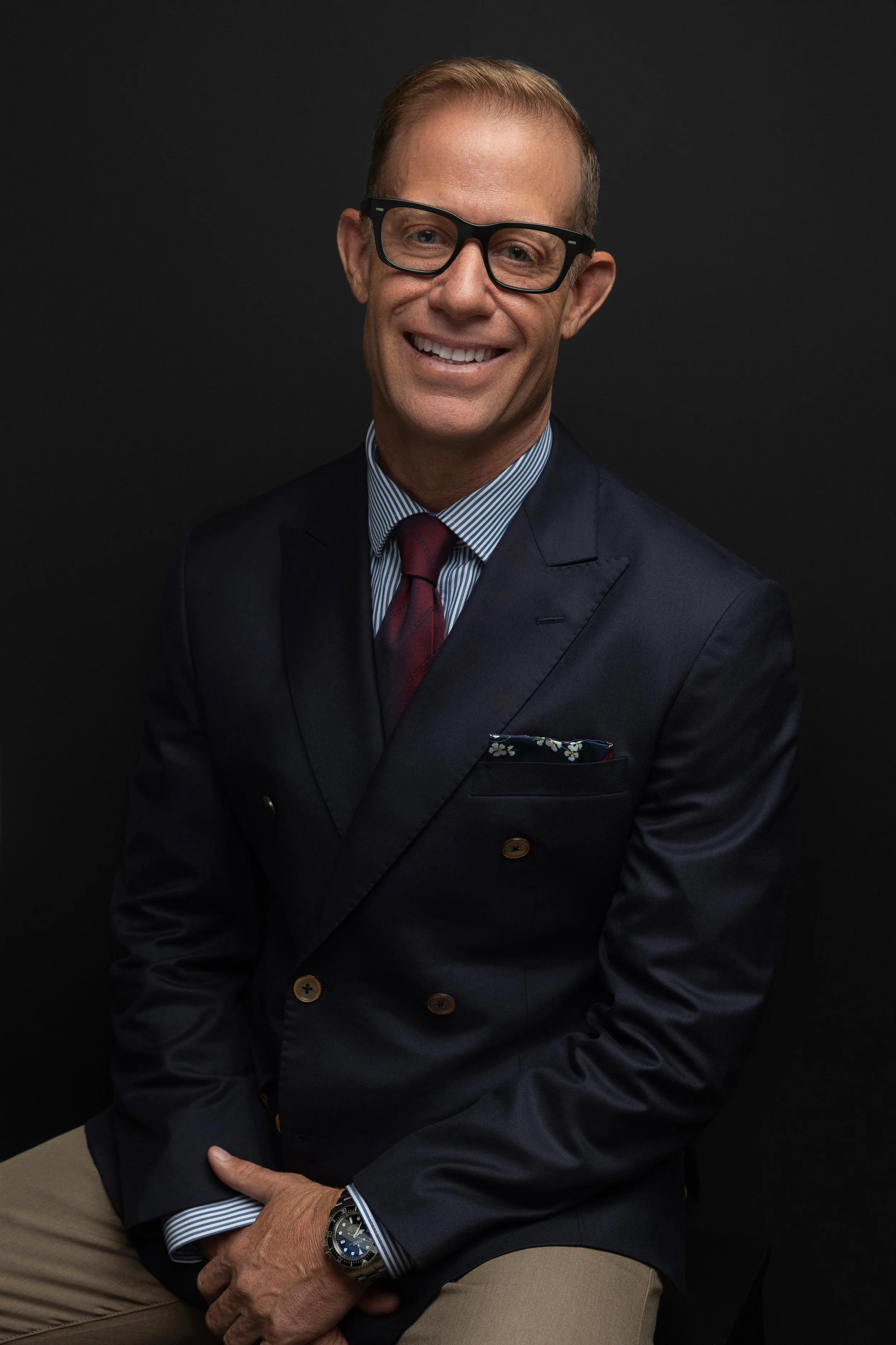 Professional studio headshot of a confident man wearing glasses and a tailored suit against a dark background, photographed by Hadonica's photography in Memphis Tennessee top headshot photographer 