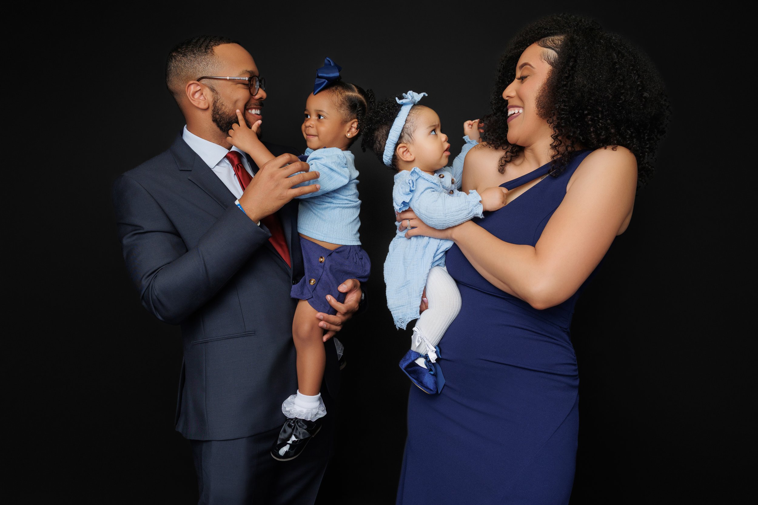 Parents holding twin baby girls during a formal studio family portrait session in Memphis TN
