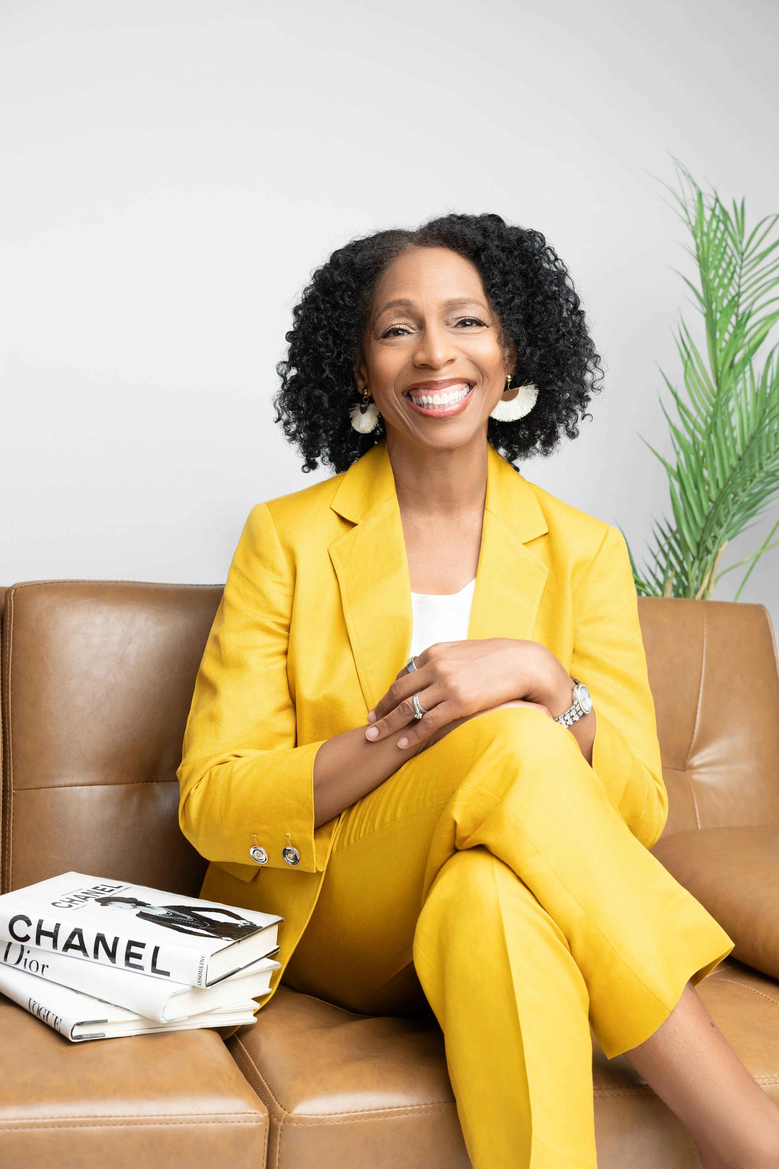 Professional therapist personal branding portrait of a confident woman in a yellow suit sitting on a couch in a Memphis photography studio