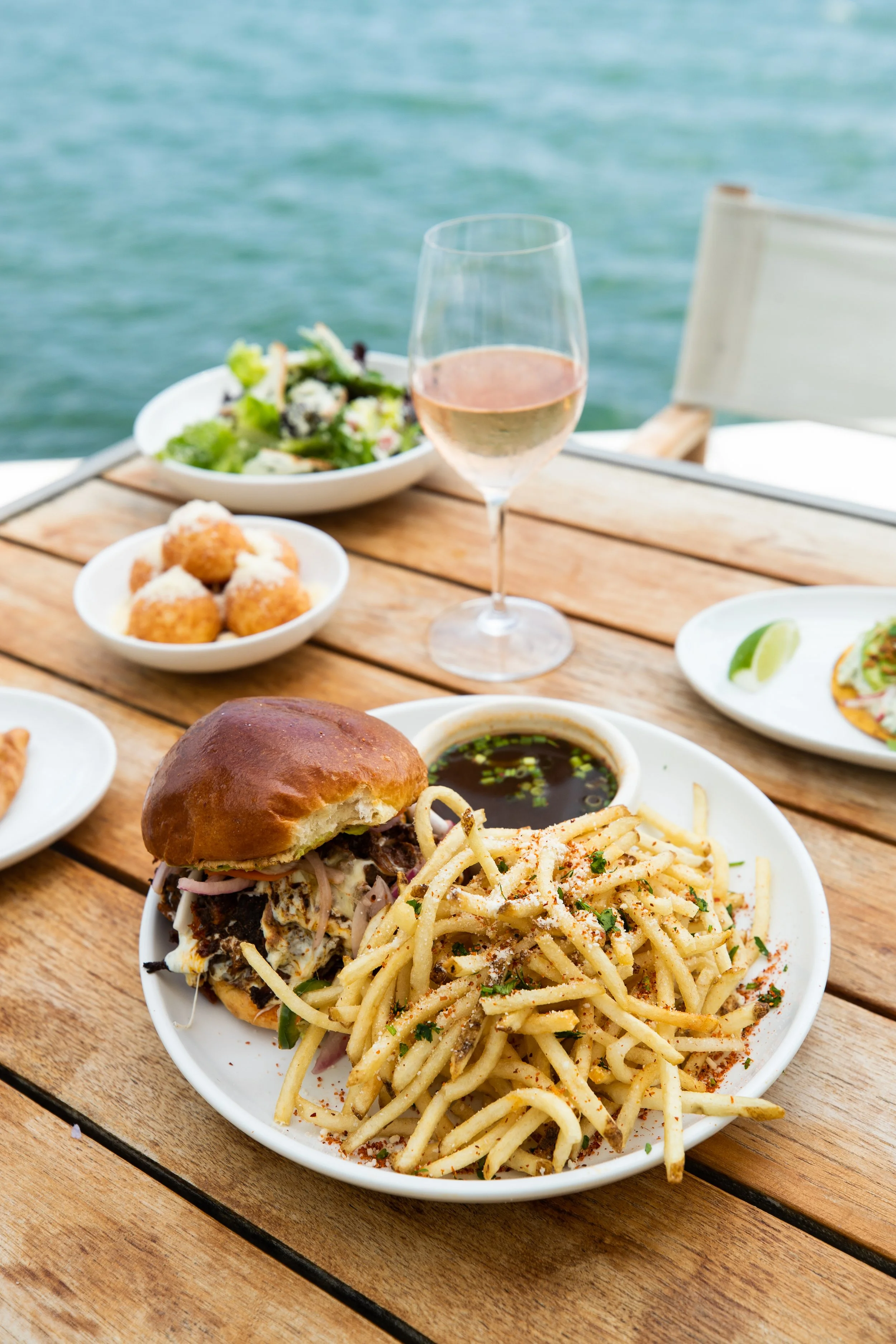 A delicious burger with a side of skinny fries, garnished with lettuce and tomato. Amara at paraiso.