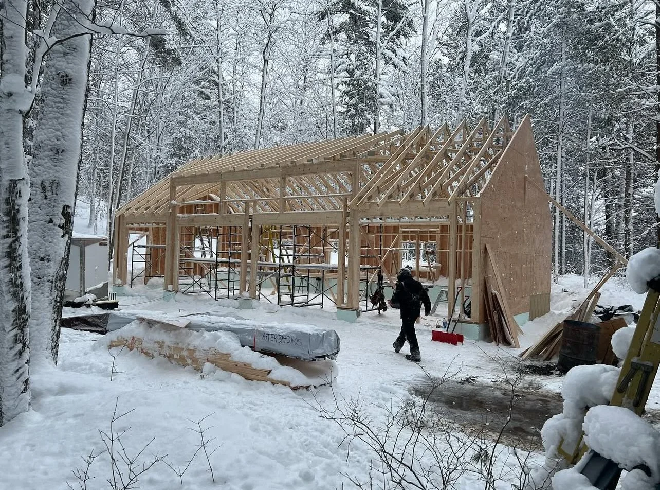 Framed outbuilding under construction among Muskoka trees in winter