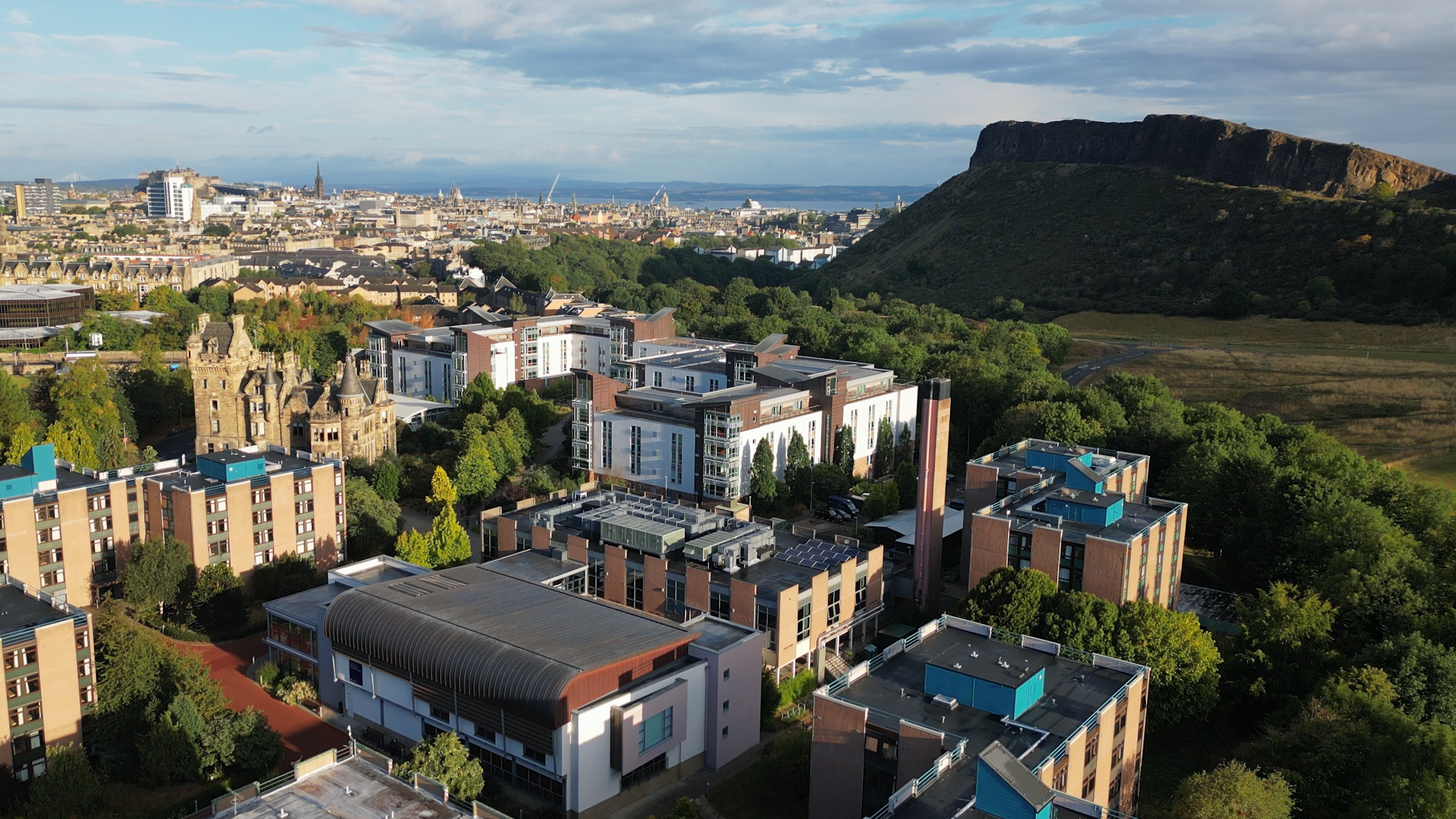 An aerial view from a drone shows the John McIntyre Conference Centre on  the University of Edinburgh Pollock Campus. The shots looks towards Leith, with Salisbury Crags in the foreground. The drone shot was taken by Walker Creative Video Production