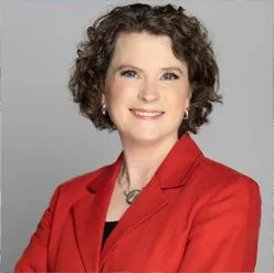 Headshot of Mary wearing a red jacket and black top.