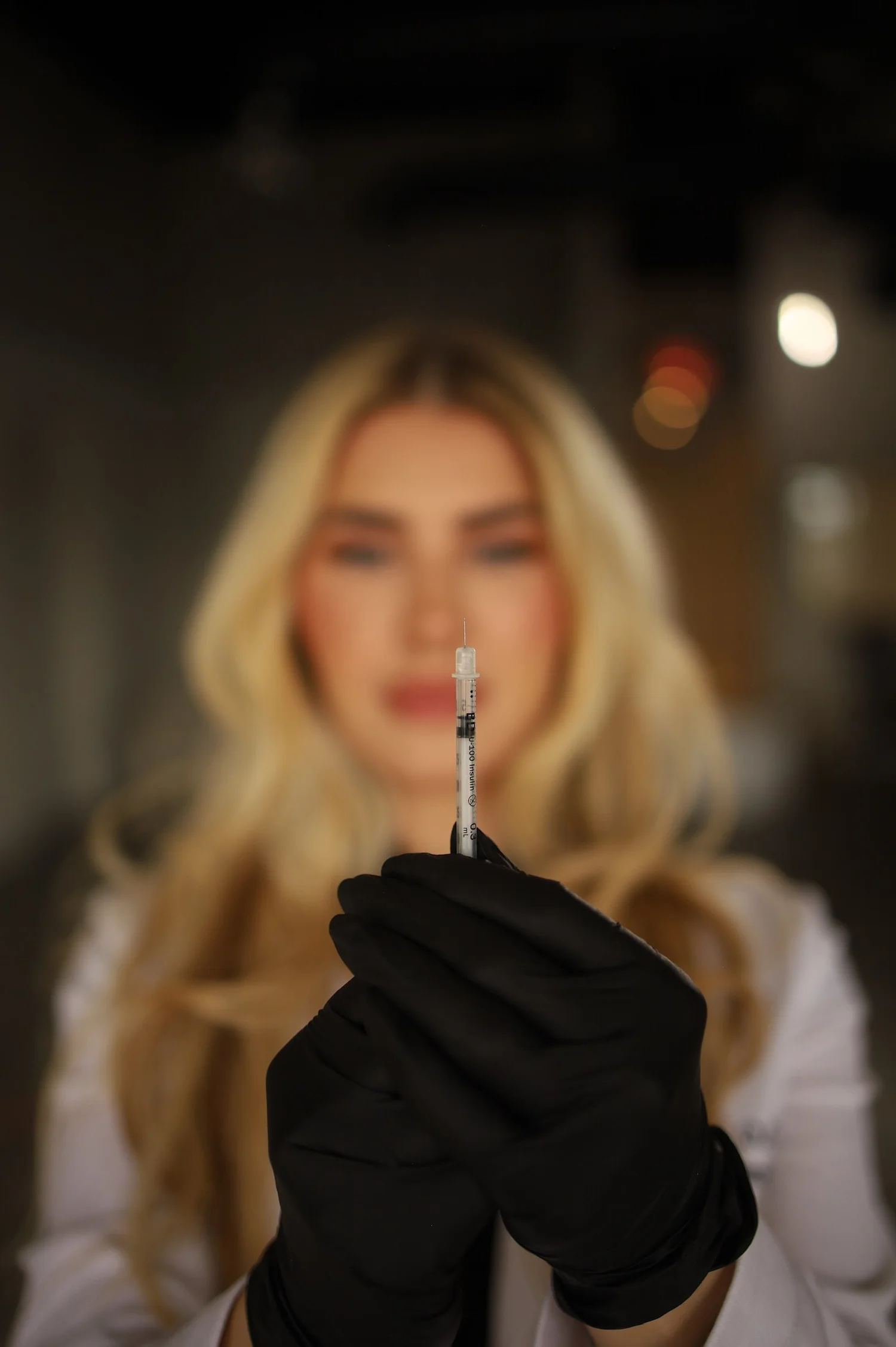 Dr. Alex, DNP, APRN, FNP-C, founder of Blonde Girl Aesthetics, holding a syringe