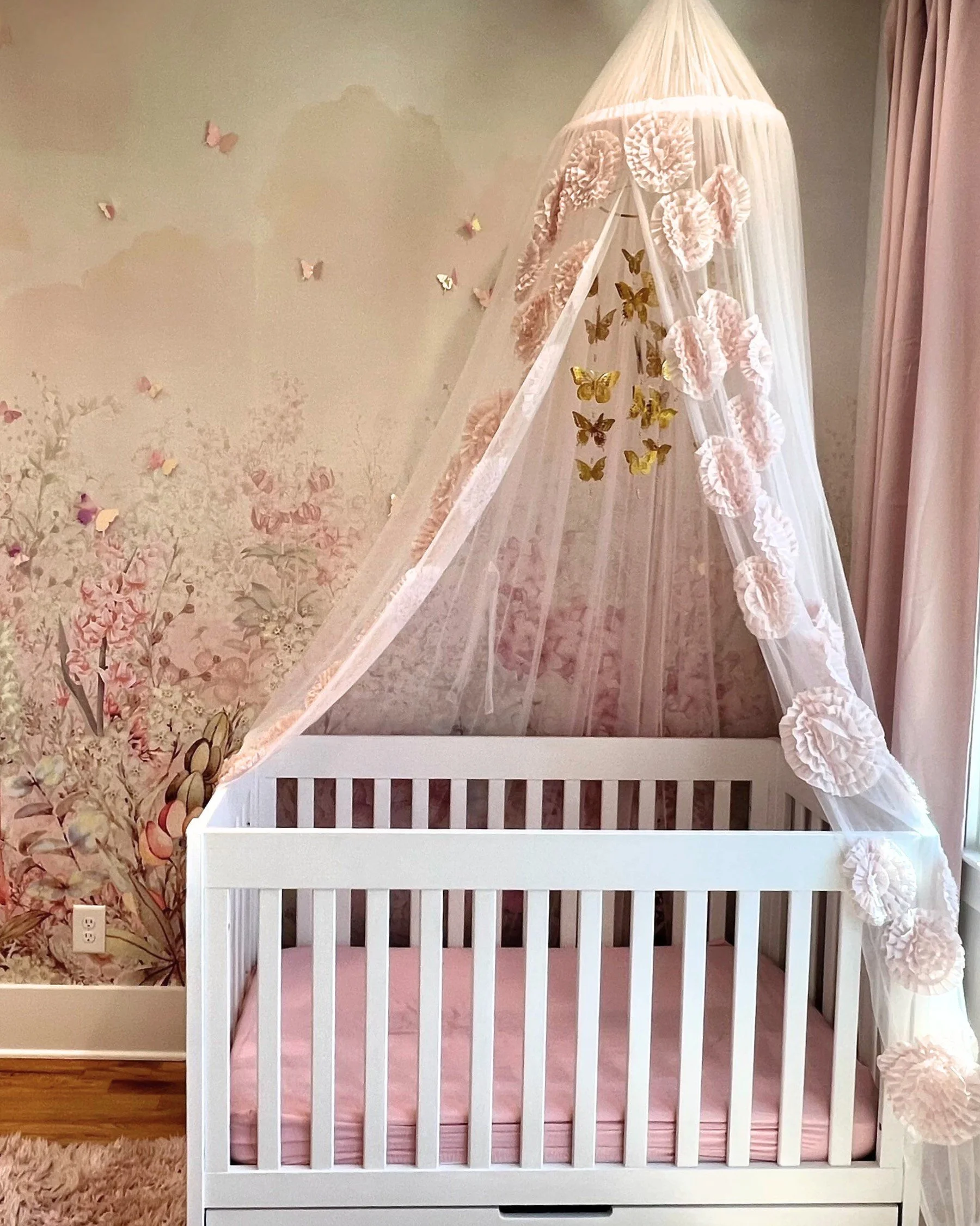 Canopy crib layered against the floral mural in the Butterfly Room