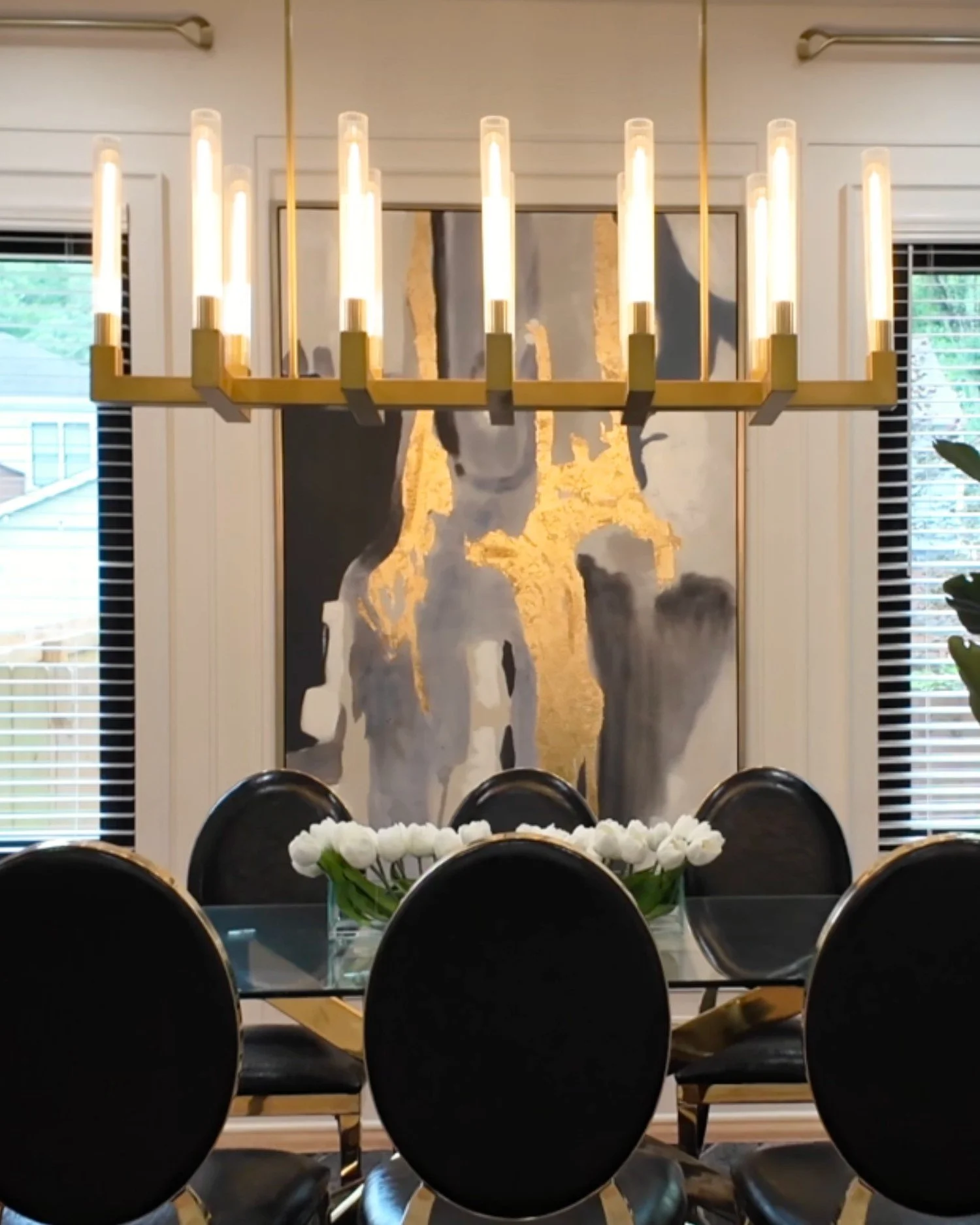 Monument Avenue dining room with chandelier, glass table, and black and gold chairs