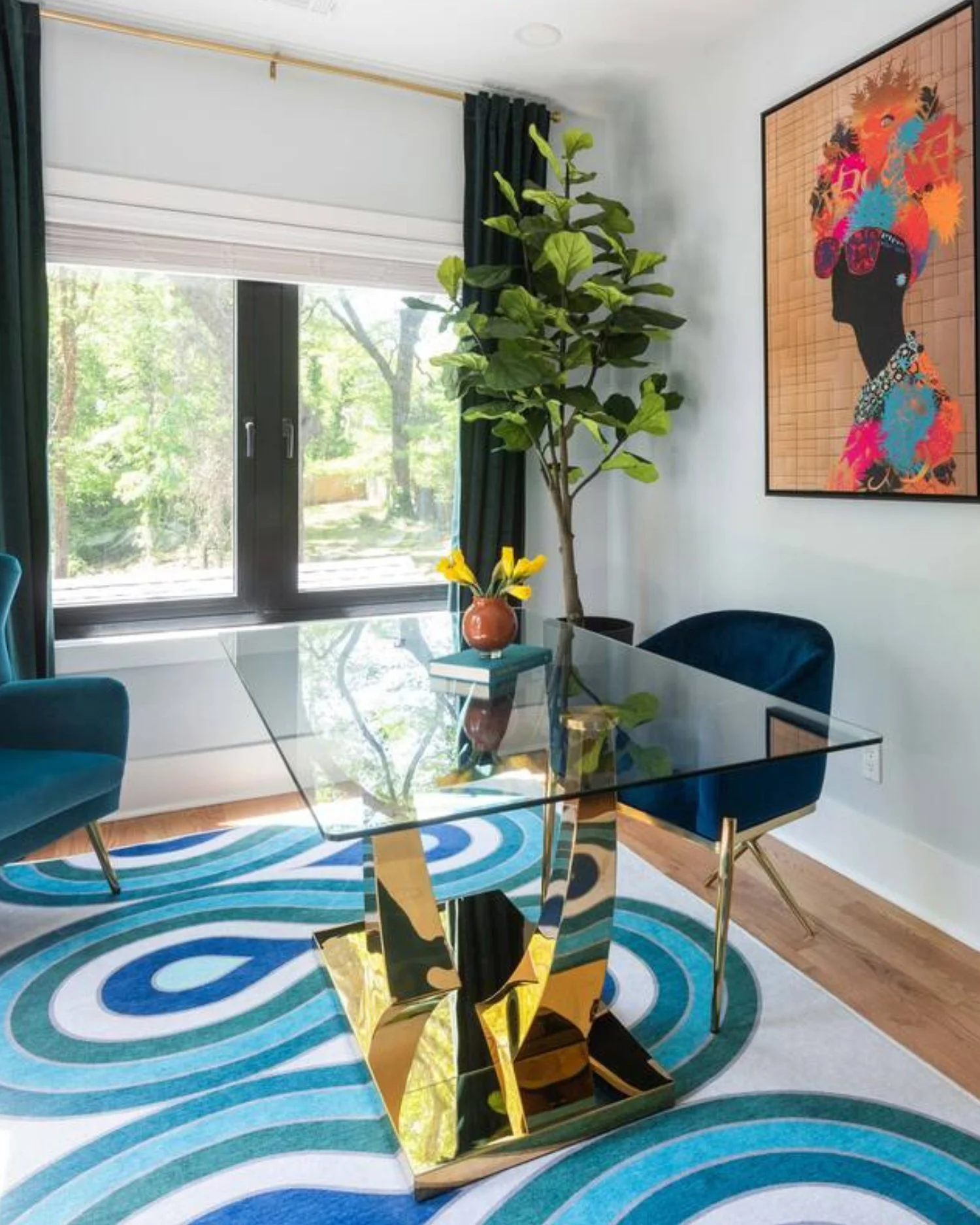 Ridgedale office vignette with glass desk, sculptural gold base, blue chairs, and abstract artwork