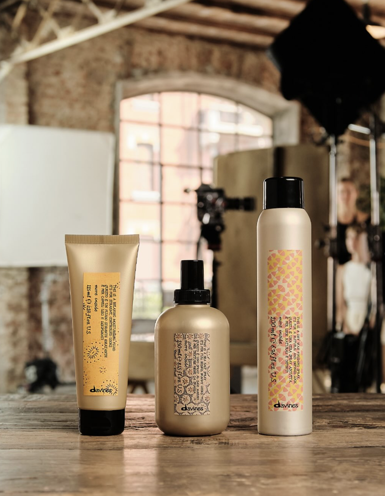 Davines haircare products displayed on a rustic wooden table inside a warm studio setting