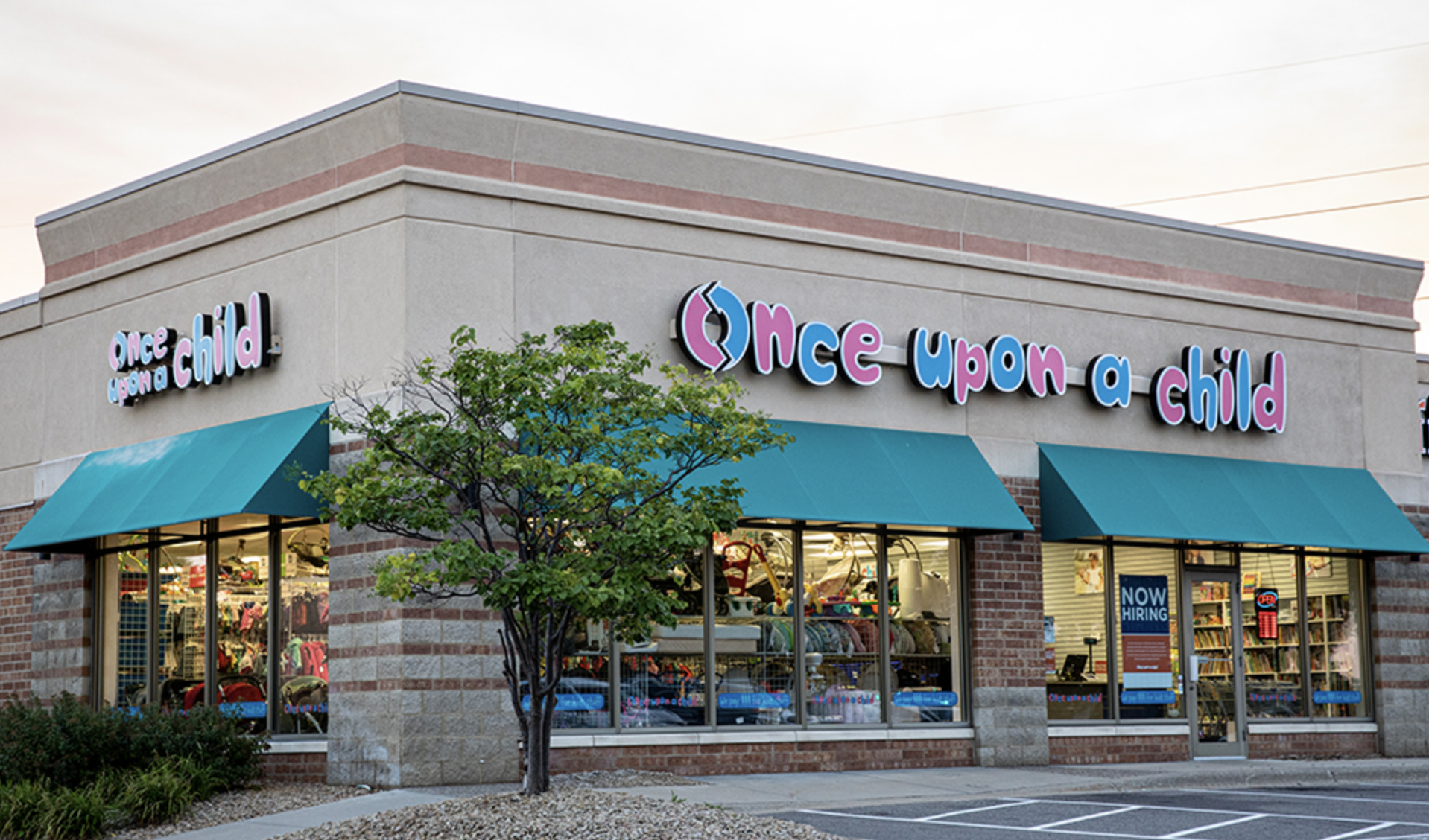 Once Upon a Child resale store exterior with teal awnings and storefront windows filled with secondhand children’s clothing, toys and baby gear.