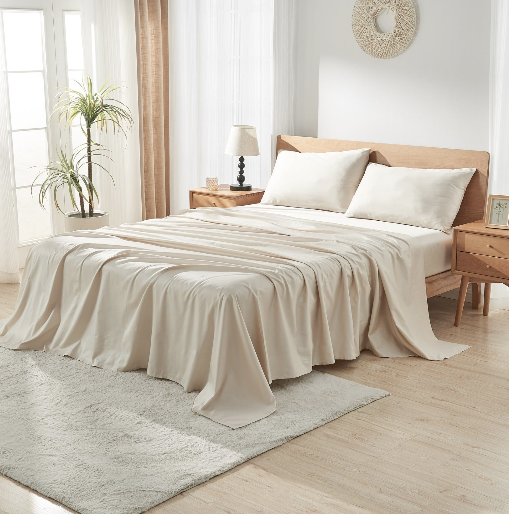 Bed with soft beige sheets and pillows in a sunlit bedroom with warm wood furniture and neutral decor.