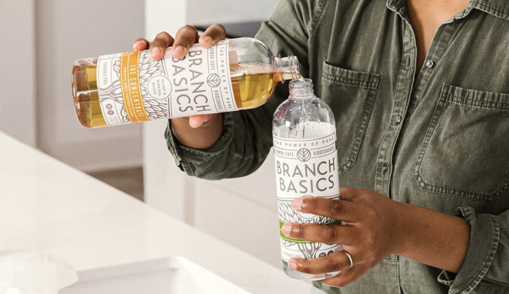Person pouring Branch Basics cleaning concentrate into a reusable bottle, illustrating a refill-based, human-safe home cleaning routine