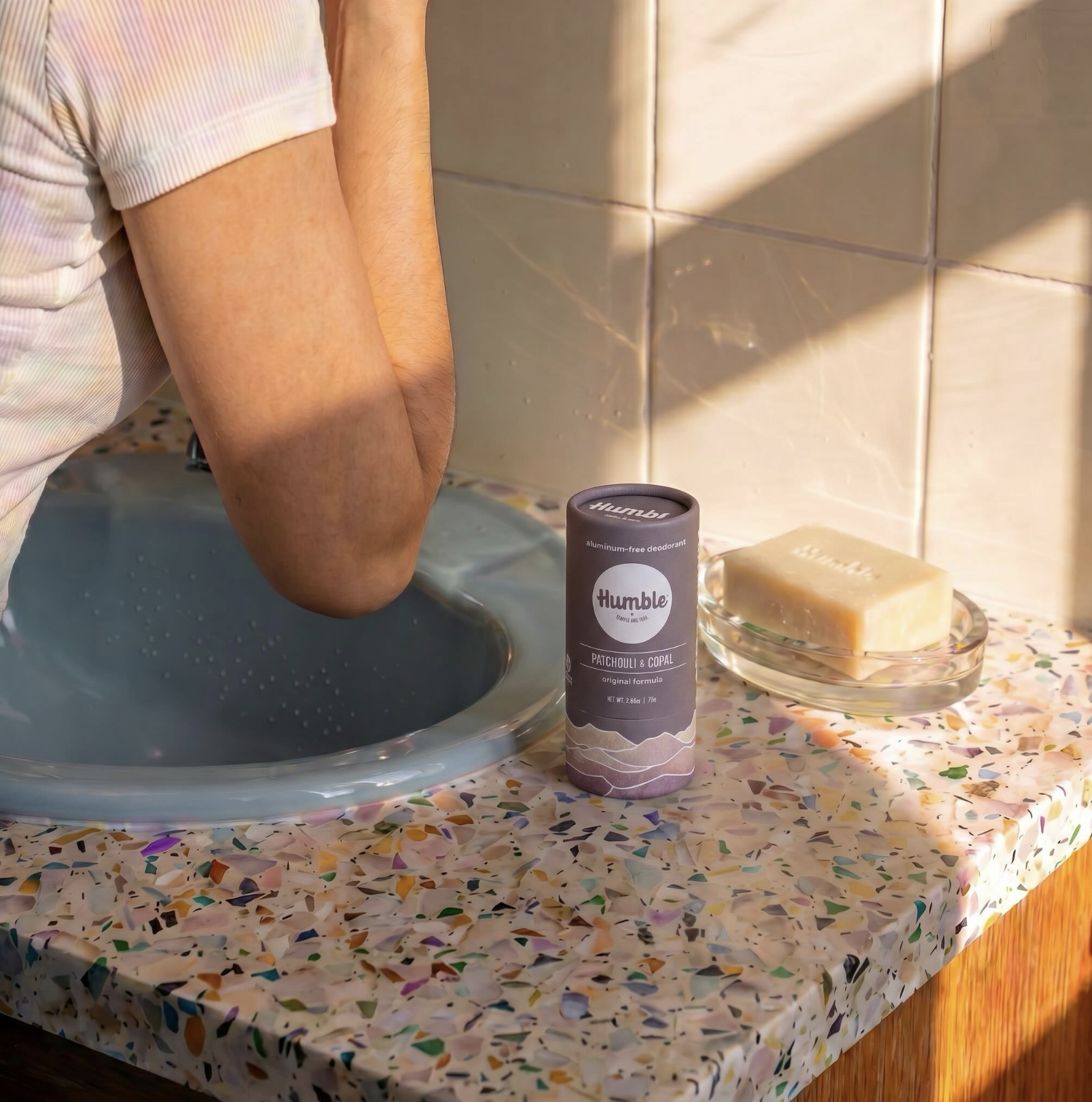 Humble Brands deodorant and bar soap displayed on a bathroom countertop beside a sink, illustrating an everyday personal care routine with thoughtfully designed products.