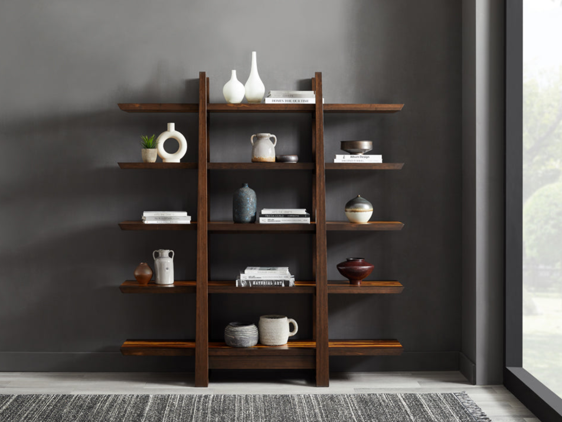 Greenington dark wood shelving unit styled with ceramic decor, books and neutral accents against a charcoal wall in a modern living space