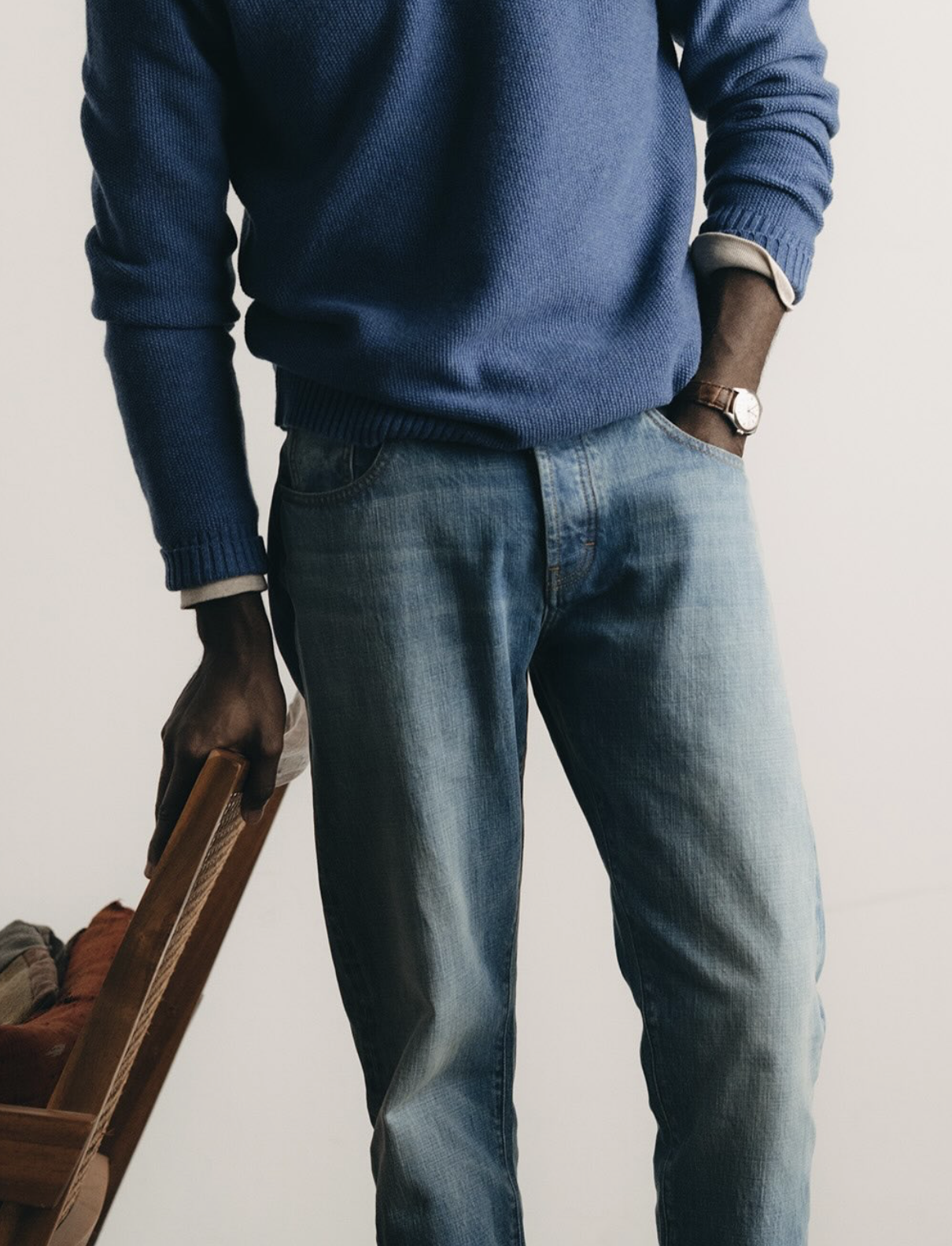 Detail shot of a man wearing blue knit sweater and faded denim jeans