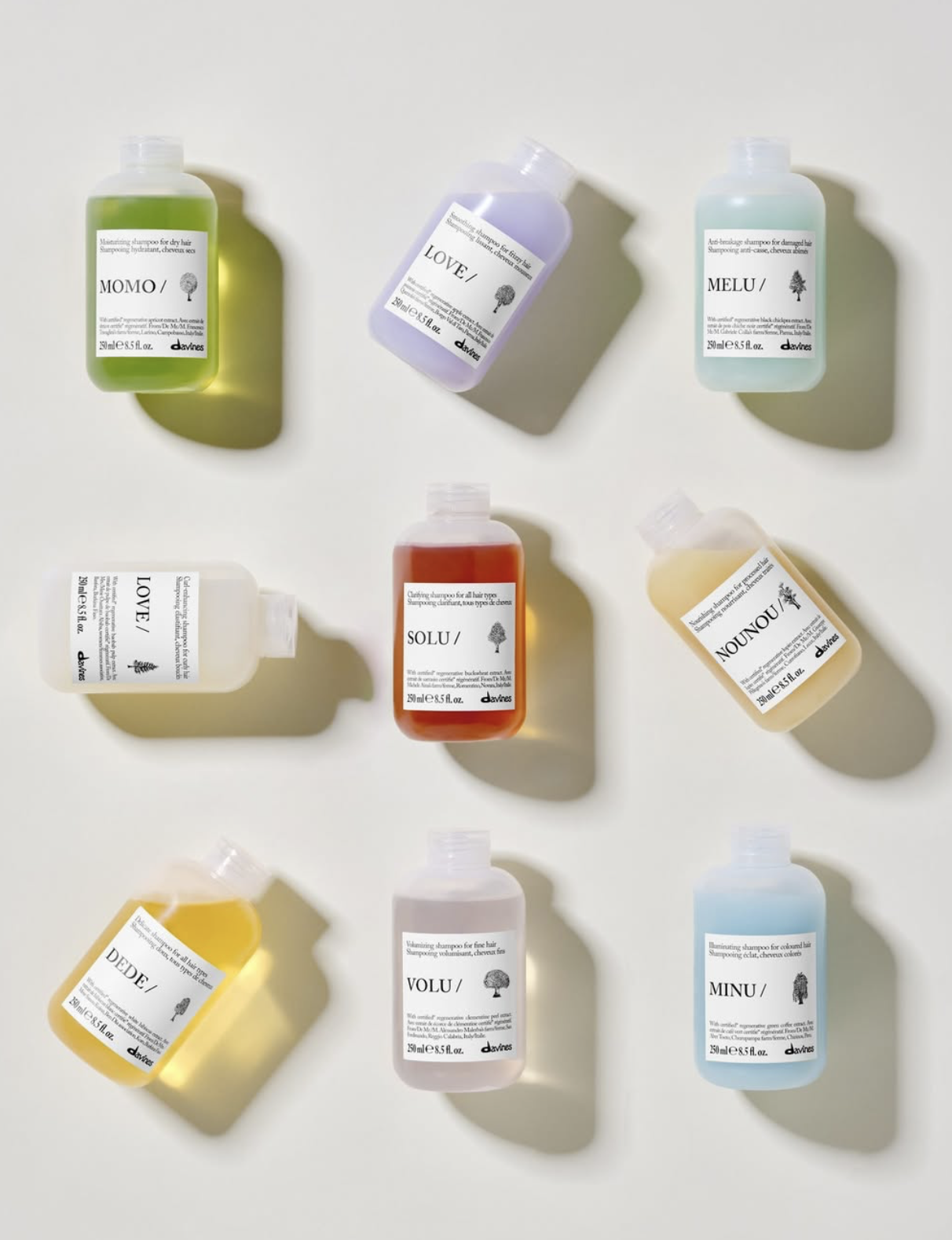 Colorful Davines Essential Haircare shampoo bottles arranged on a white background with soft natural shadows