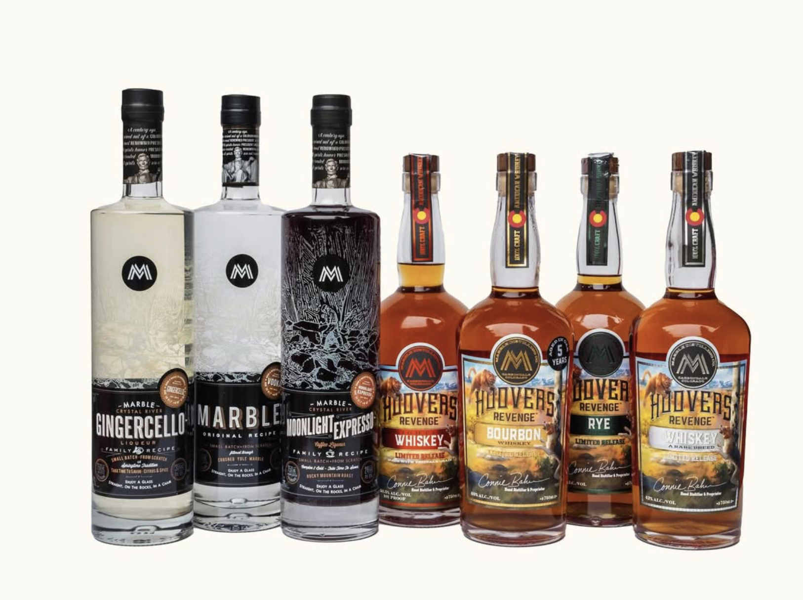 A lineup of Marble Distilling spirits including vodka, liqueurs and multiple whiskey expressions displayed against a neutral background.