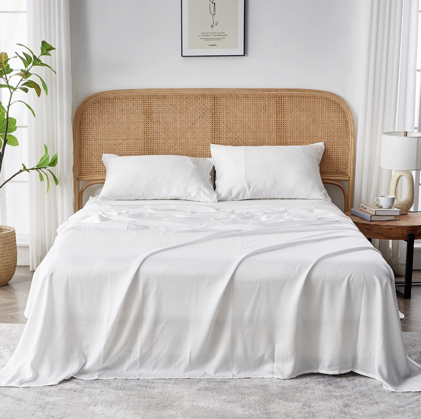 Bed with white eucalyptus sheets and matching pillows on a woven rattan headboard in a bright, minimalist bedroom.