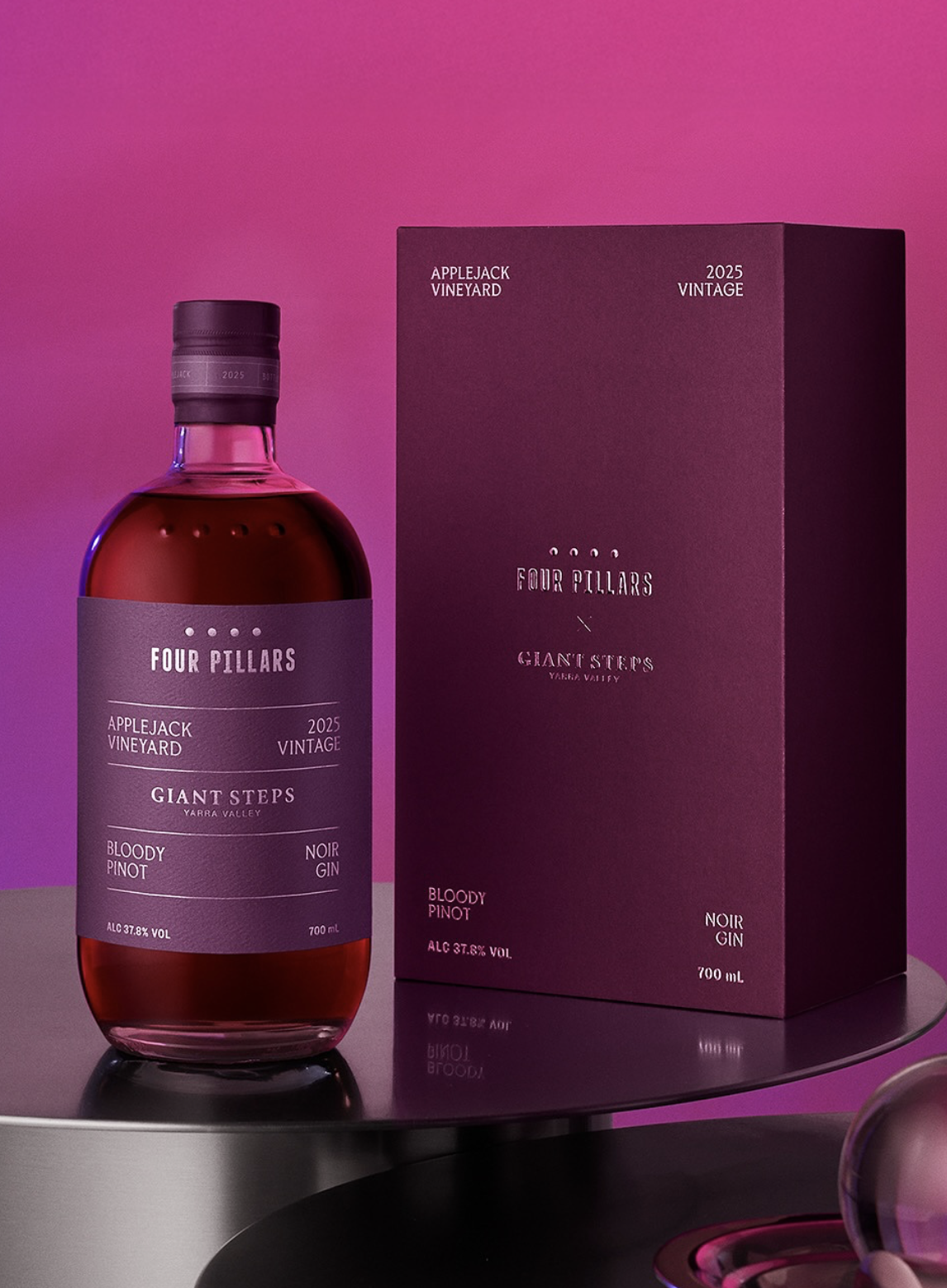 Bottle of Four Pillars Giant Steps Bloody Pinot Noir Gin next to its box packaging against a vibrant pink background