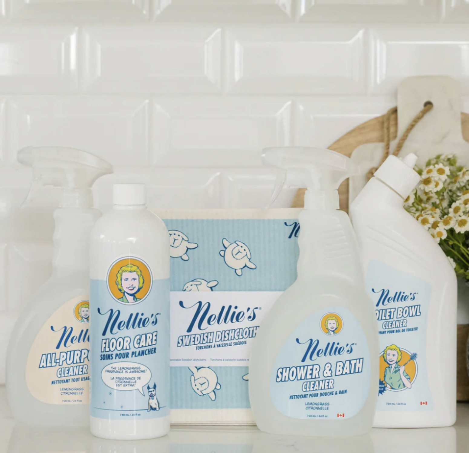 Nellie’s household cleaning products, including all-purpose cleaner, floor care, shower and bath cleaner, toilet bowl cleaner and reusable Swedish dishcloths displayed on a kitchen counter.