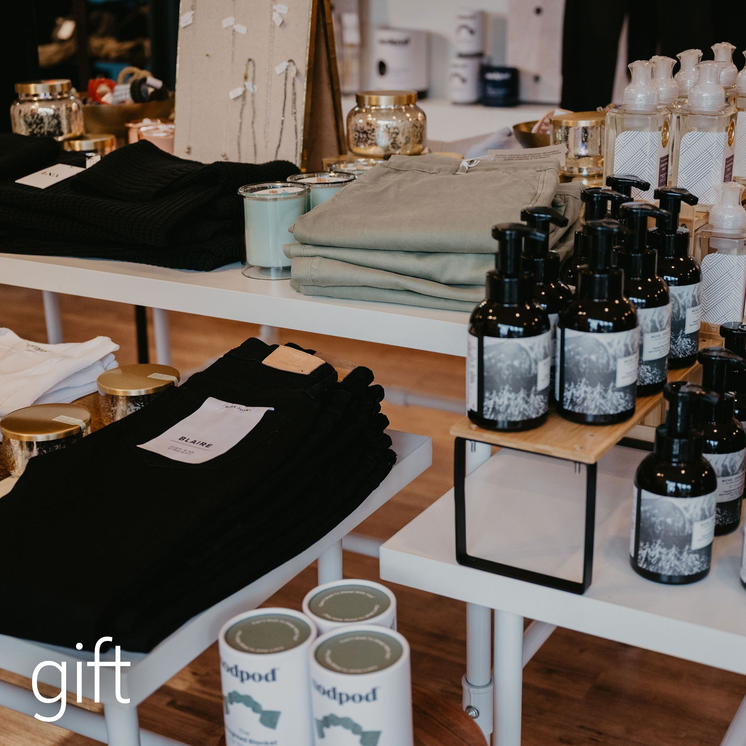 Retail display with folded clothes, candles, and bottles of soap on shelves.