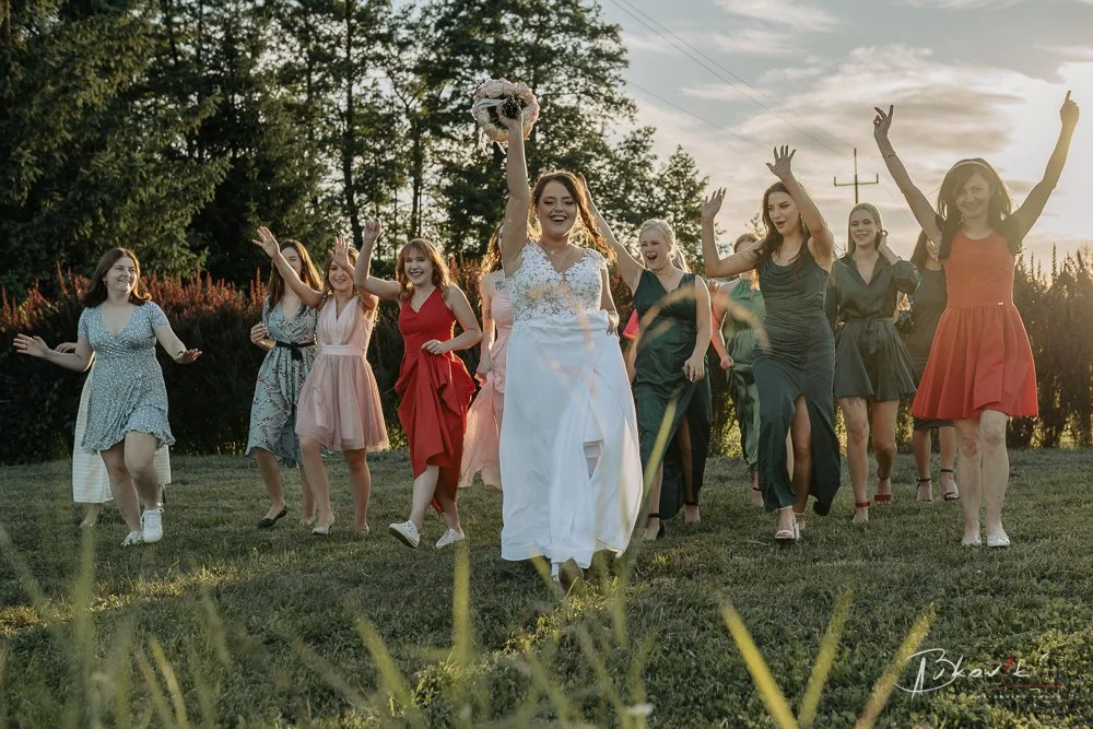 Group of women in colorful dresses walking together outdoors at sunset, celebrating.