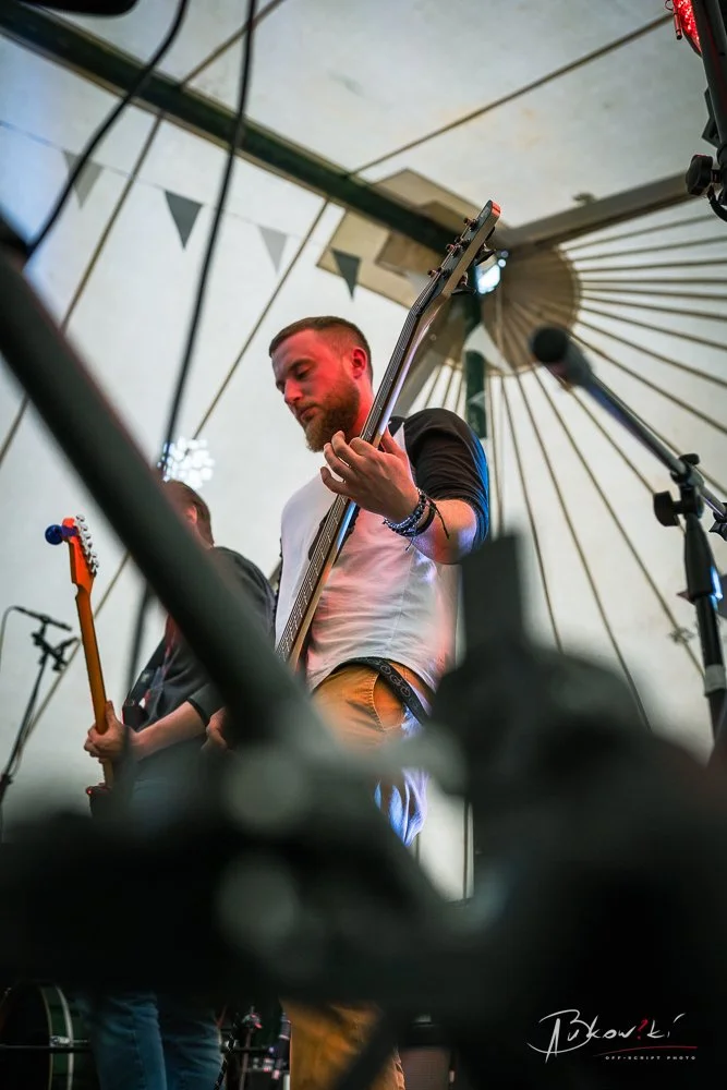 Musician playing an electric guitar under a tent at a live performance
