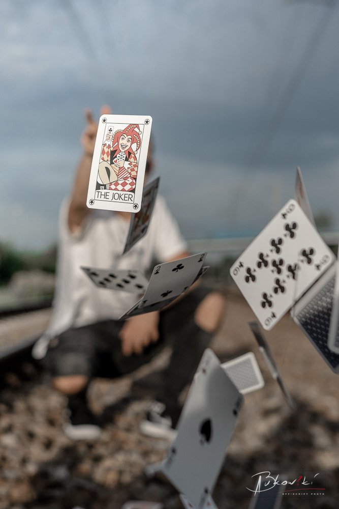 Playing cards suspended in mid-air with a blurred person in the background outdoors.