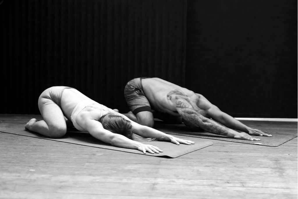 woman and man in childs pose on yoga mats