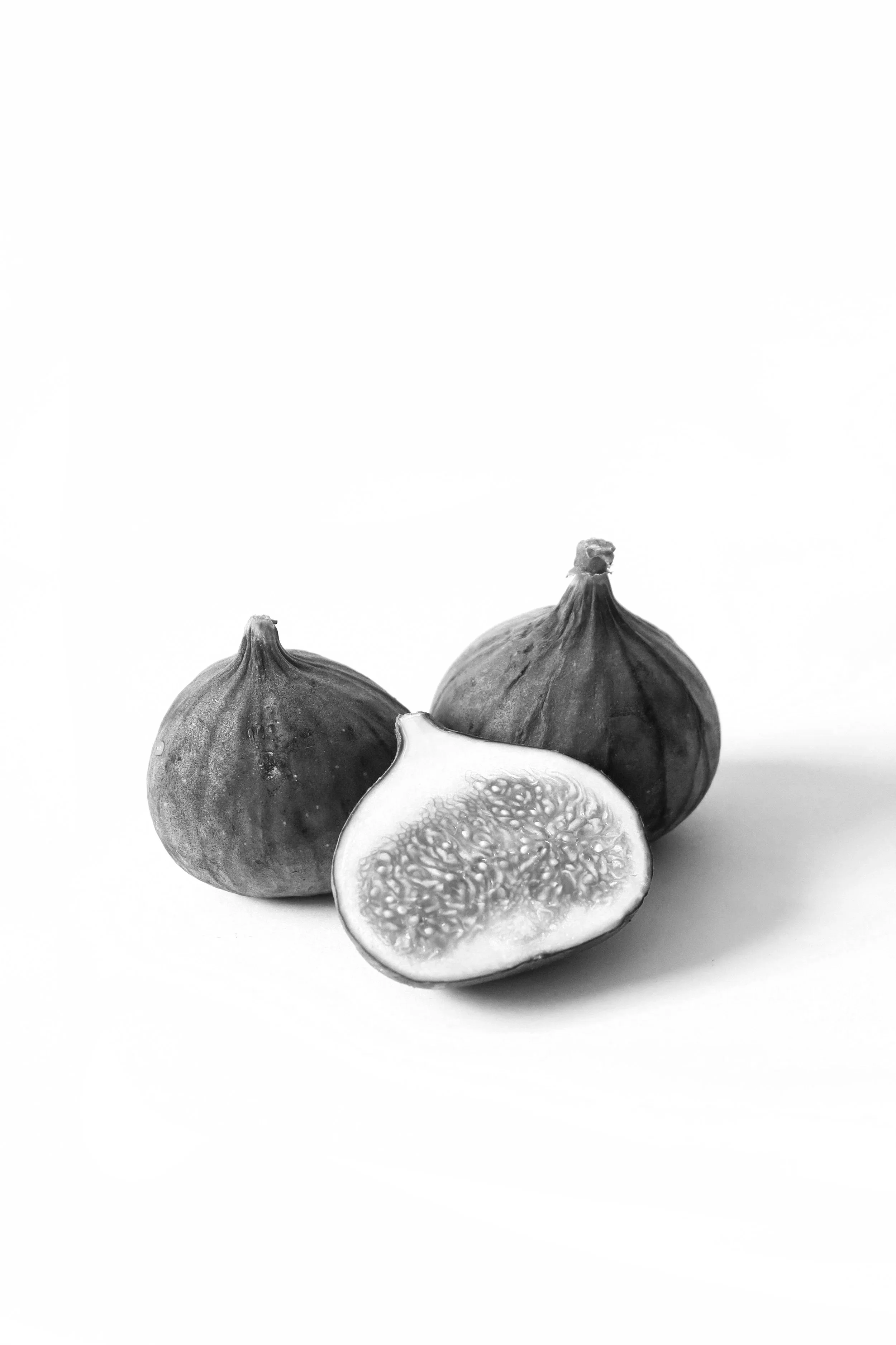two whole figs and one cut in half on white background