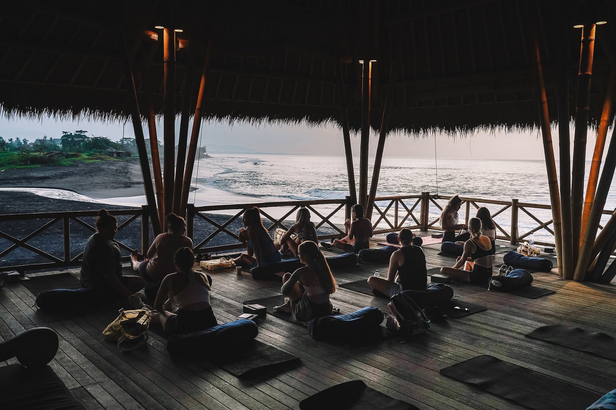 people sitting in a yoga shala at komune in bali overlooking the ocean