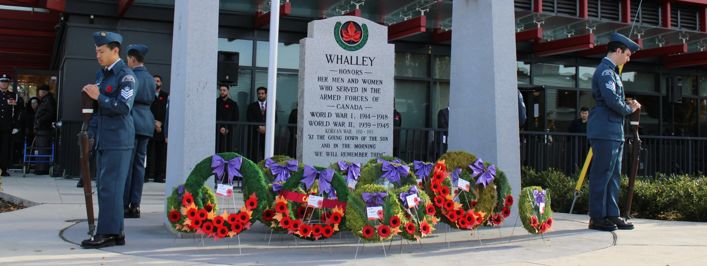 A memorial commemorates Canadian armed forces with wreaths and soldiers standing in front. The background features a red building with the sign 'Legion' and the words 'Lest We Forget'.
