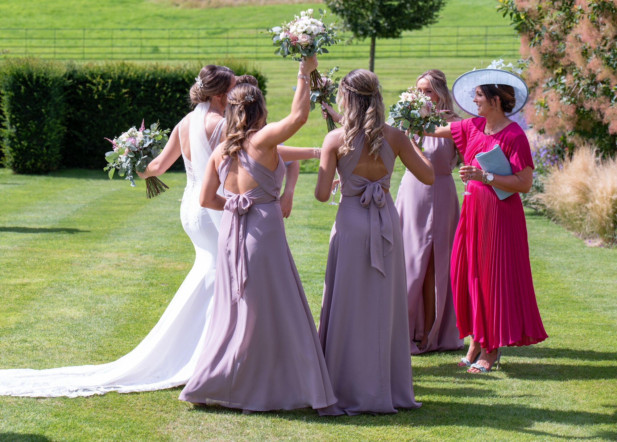  bride and bridesmaids dancing in gardens at summer wedding 